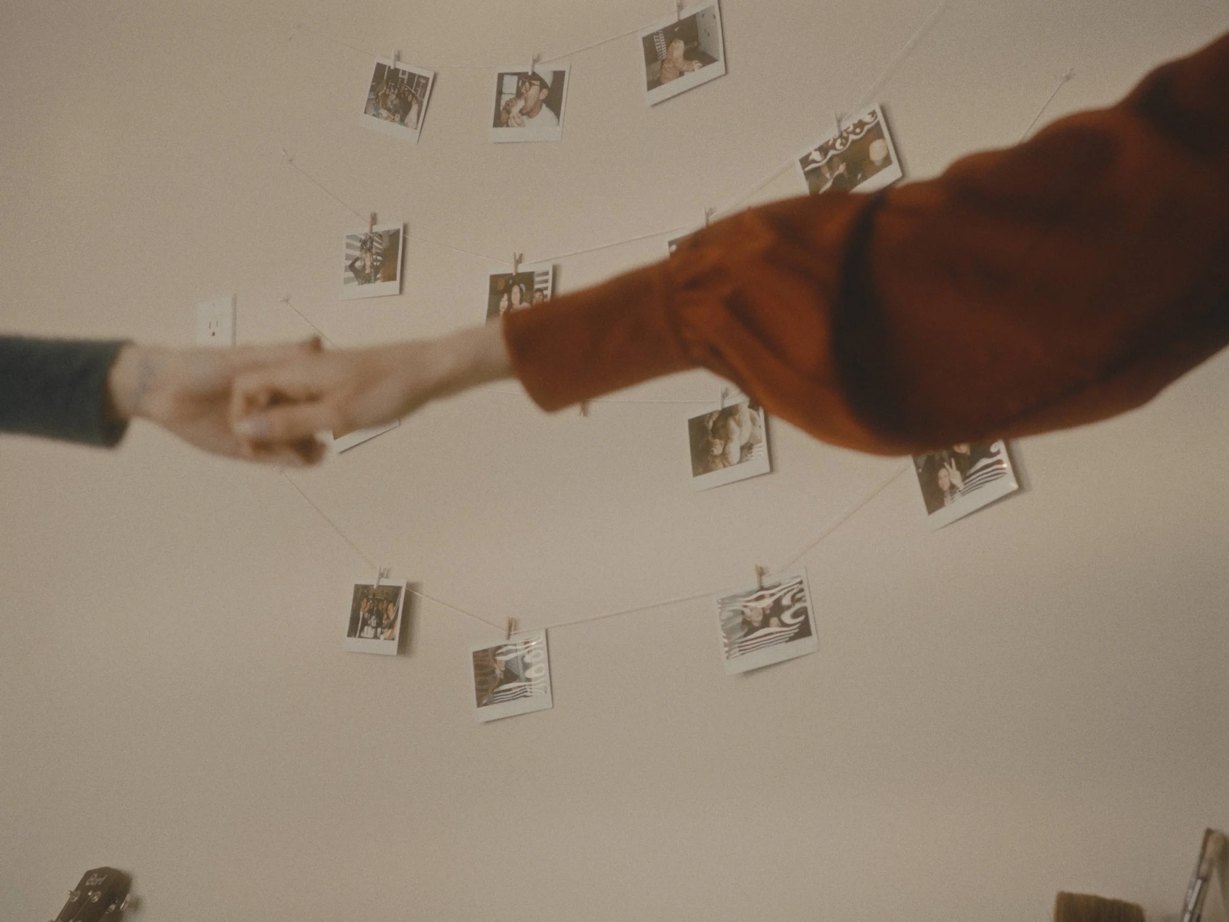 Two people shaking hands, with a wall decorated with hanging framed photographs in the background.