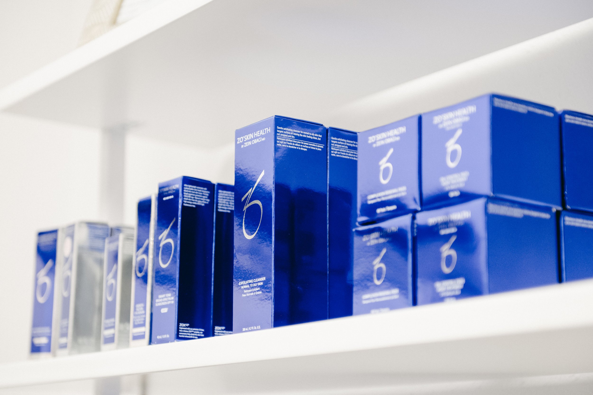 Shelf with blue boxes of ZO Skin Health product lined up in a row.