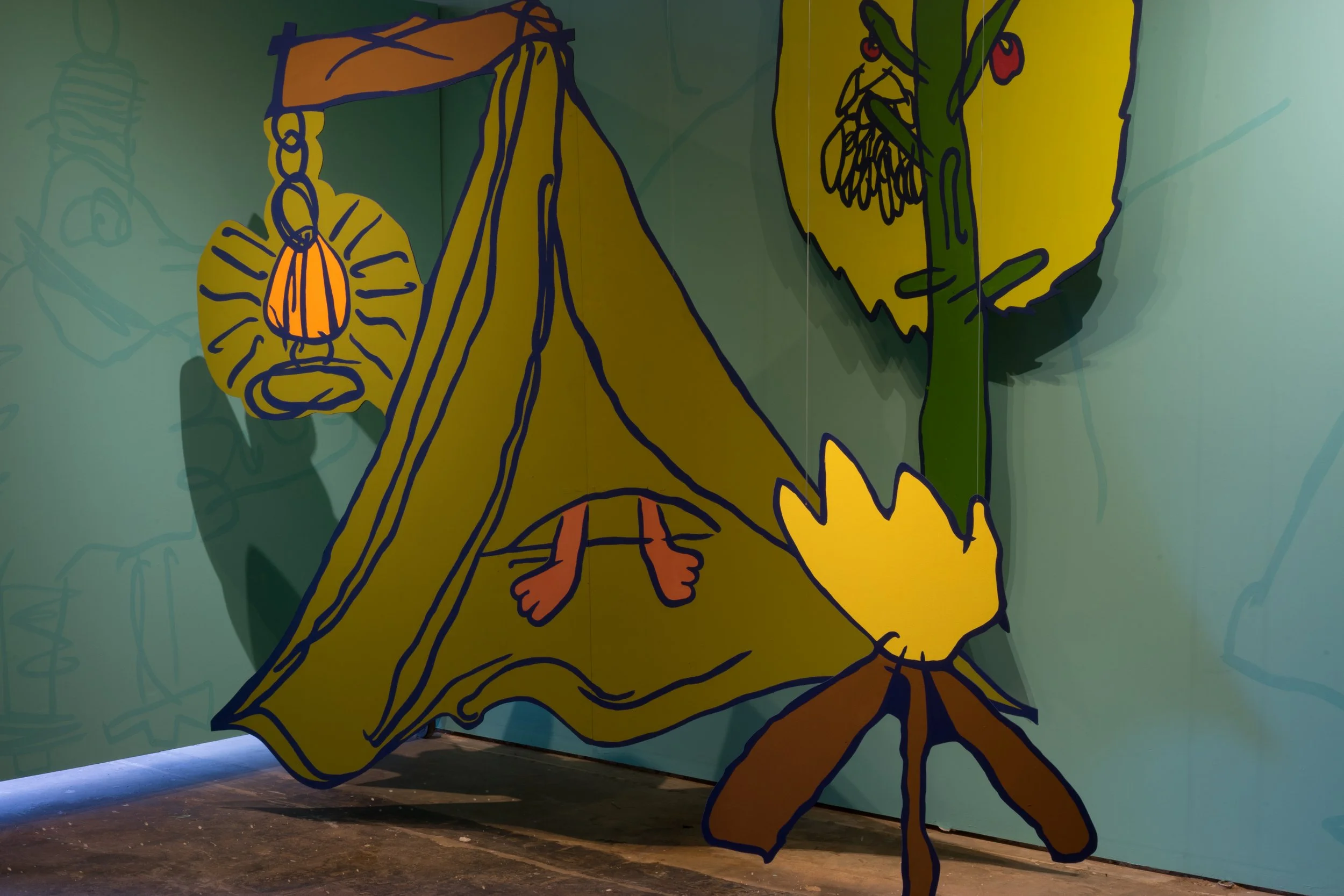 Colorful mural painting of a yellow tent with a person's legs sticking out underneath, surrounded by large yellow flowers and an orange lantern hanging from a branch, on a green wall.