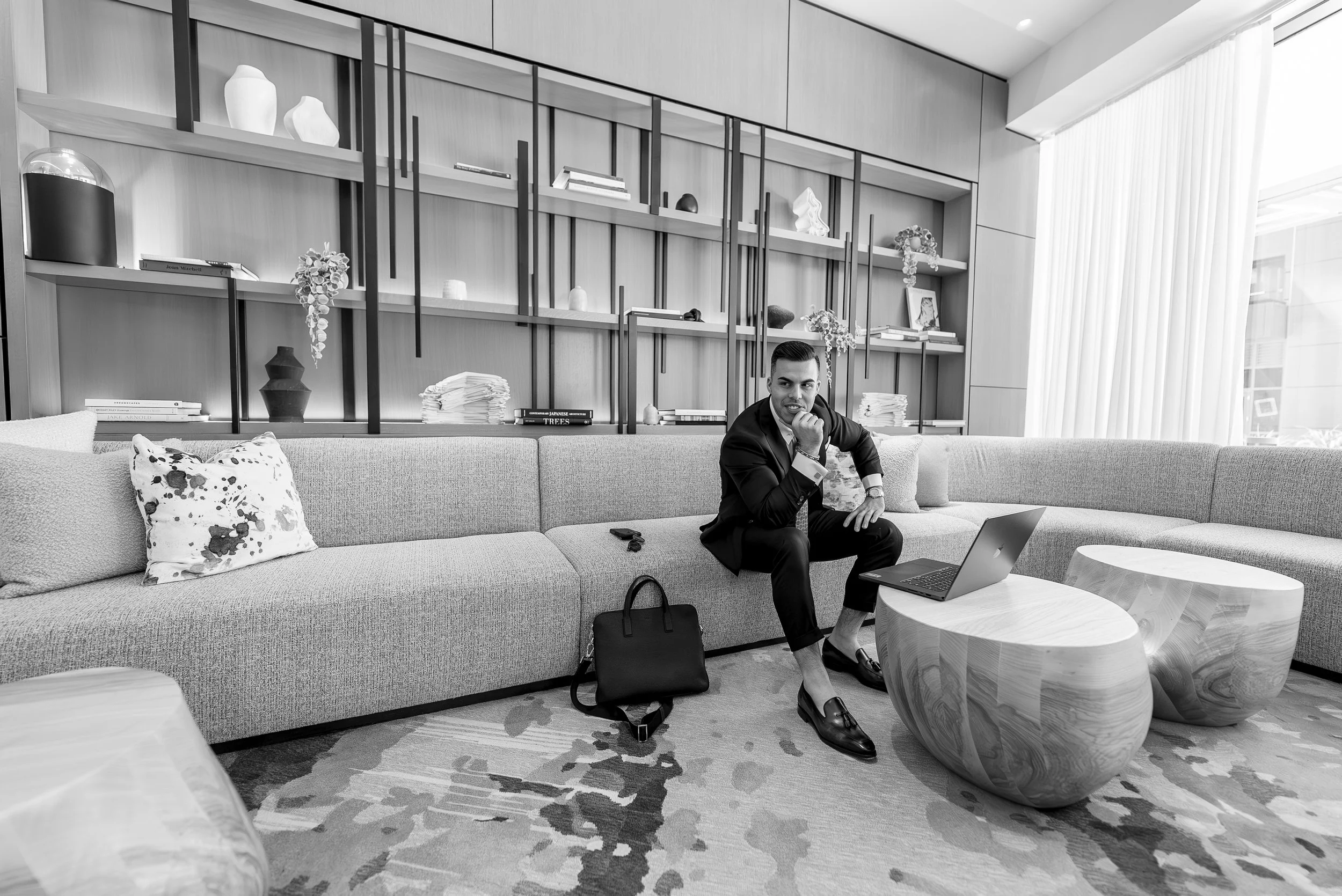 A person wearing a hoodie and jacket standing in a narrow, dimly lit stairwell with one foot on the floor and the other on a ladder, looking away from the camera.