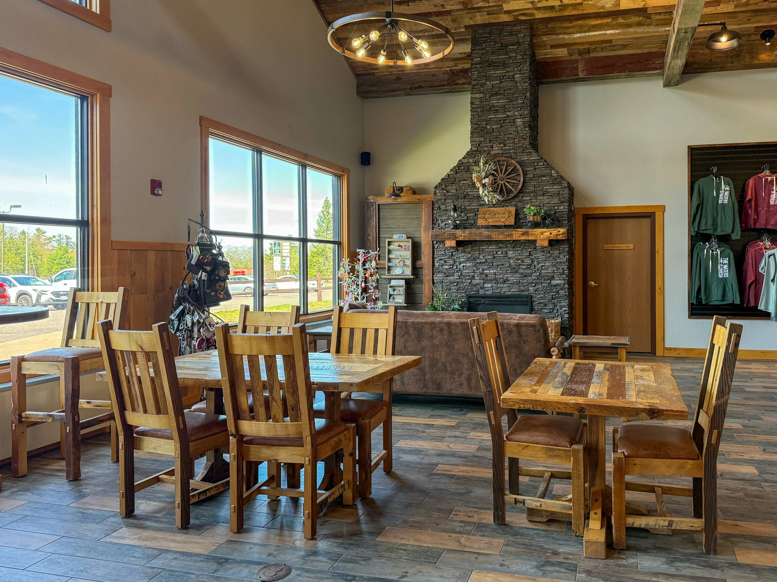 Interior of a small café with stone counter and wooden ceiling, displaying a variety of snacks and drinks. Beverages include Starbucks products, chips, and soft drinks. Shelves hold assorted merchandise like clothing and souvenirs. Posters advertise different coffee drinks.