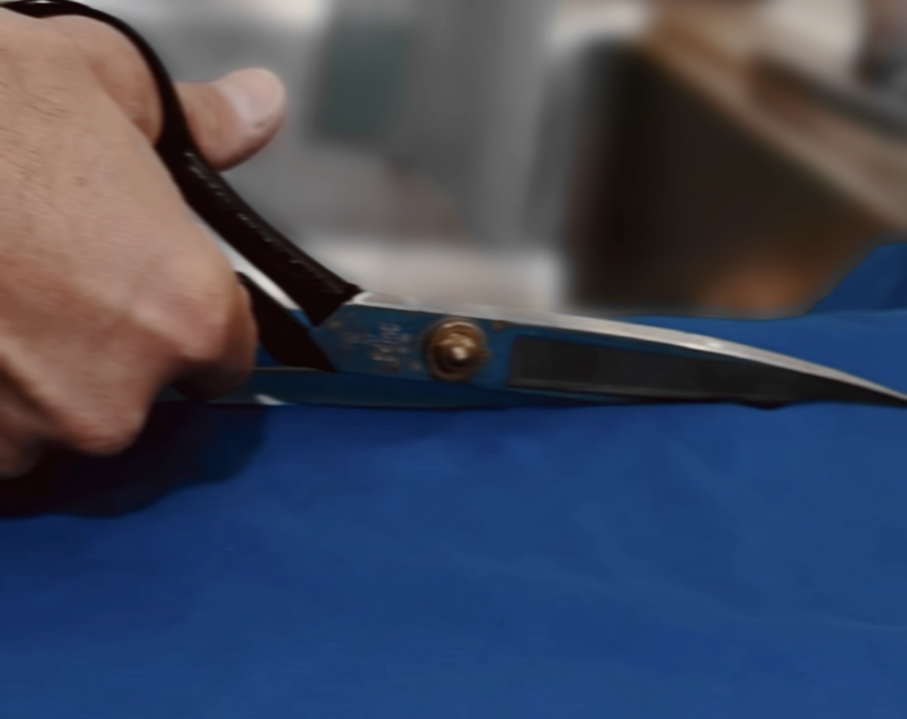 Tailor’s scissors cutting fabric in the House of Henley atelier