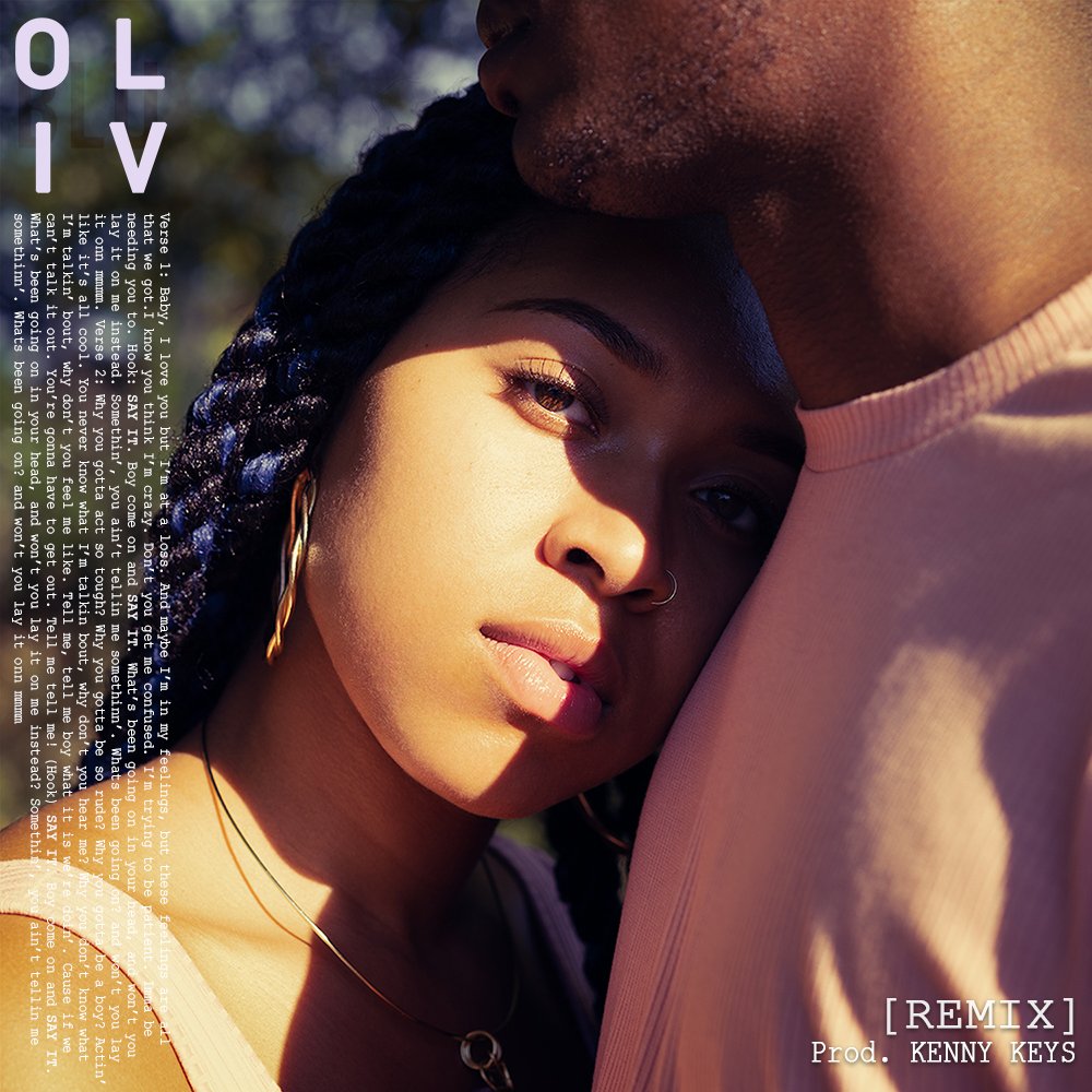 Close-up of a woman with braided hair, looking into the camera, leaning her head against a man's shoulder, with text overlay and a background of trees, promoting a remix song by Kenny Keys. Oliv Blu 'Say It' remix cover art.
