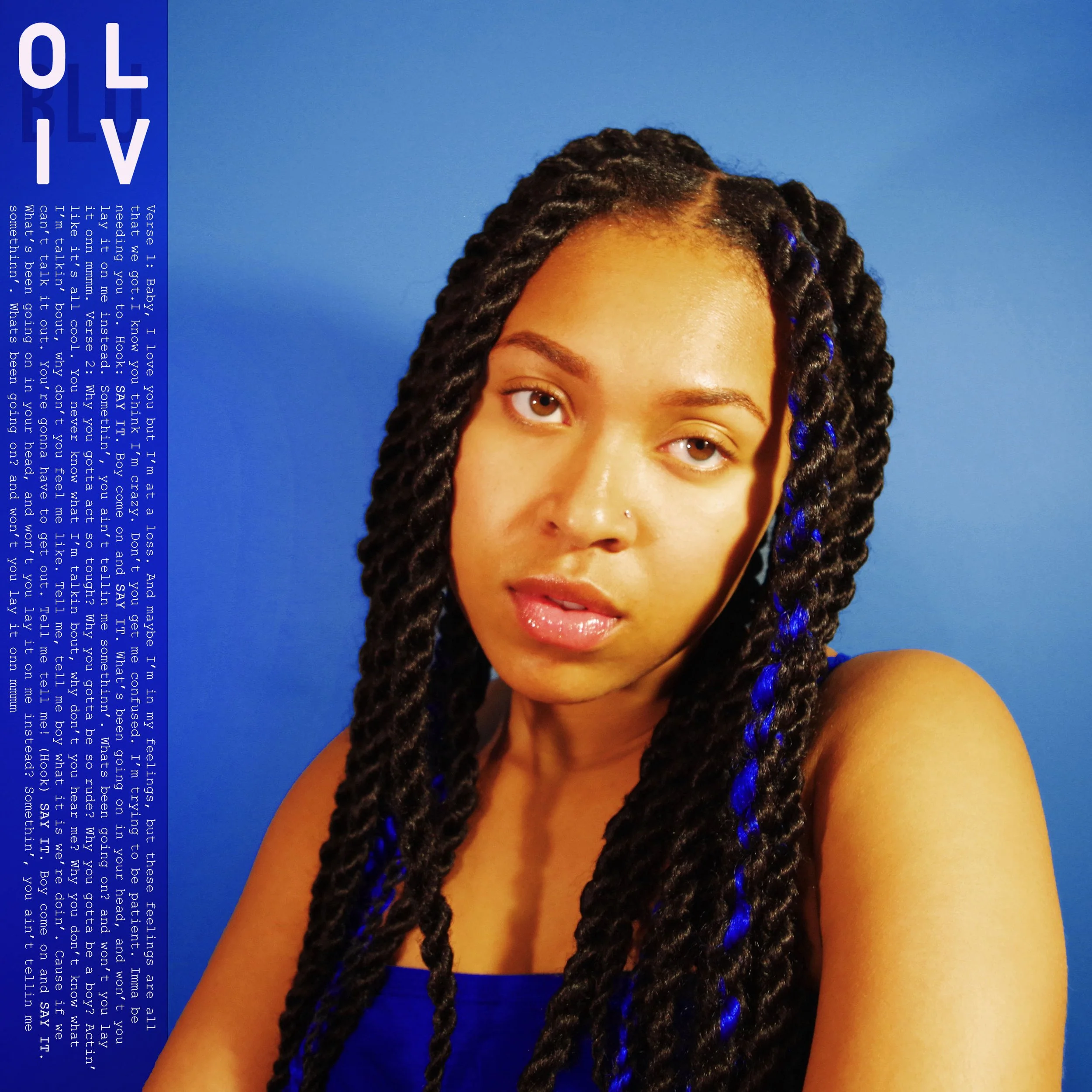 Oliv Blu Say It single. Woman with twist looking at camera in front of a blue background.