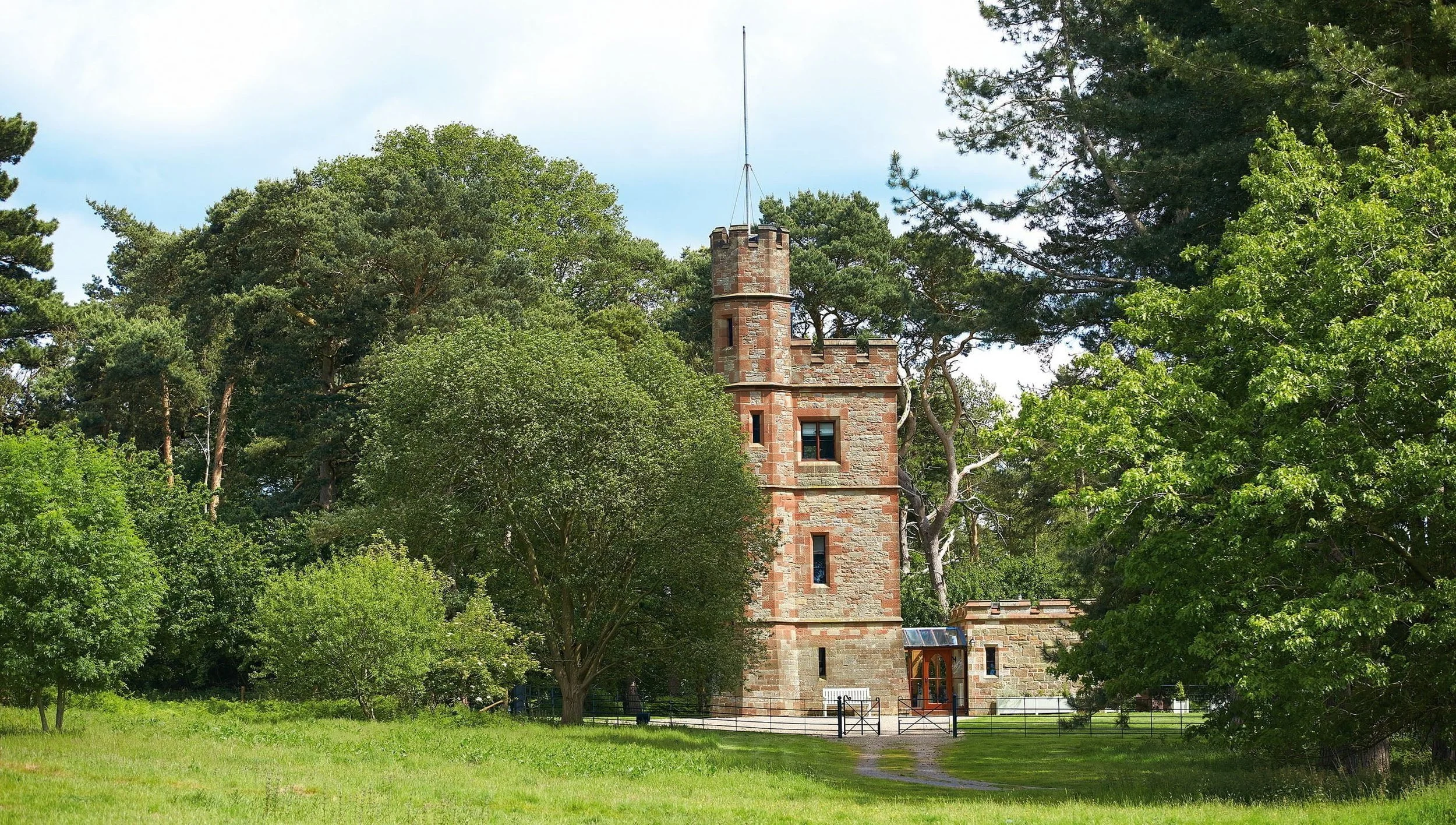 An aerial view of rocky coastline with greenish water and grassy patches on land.