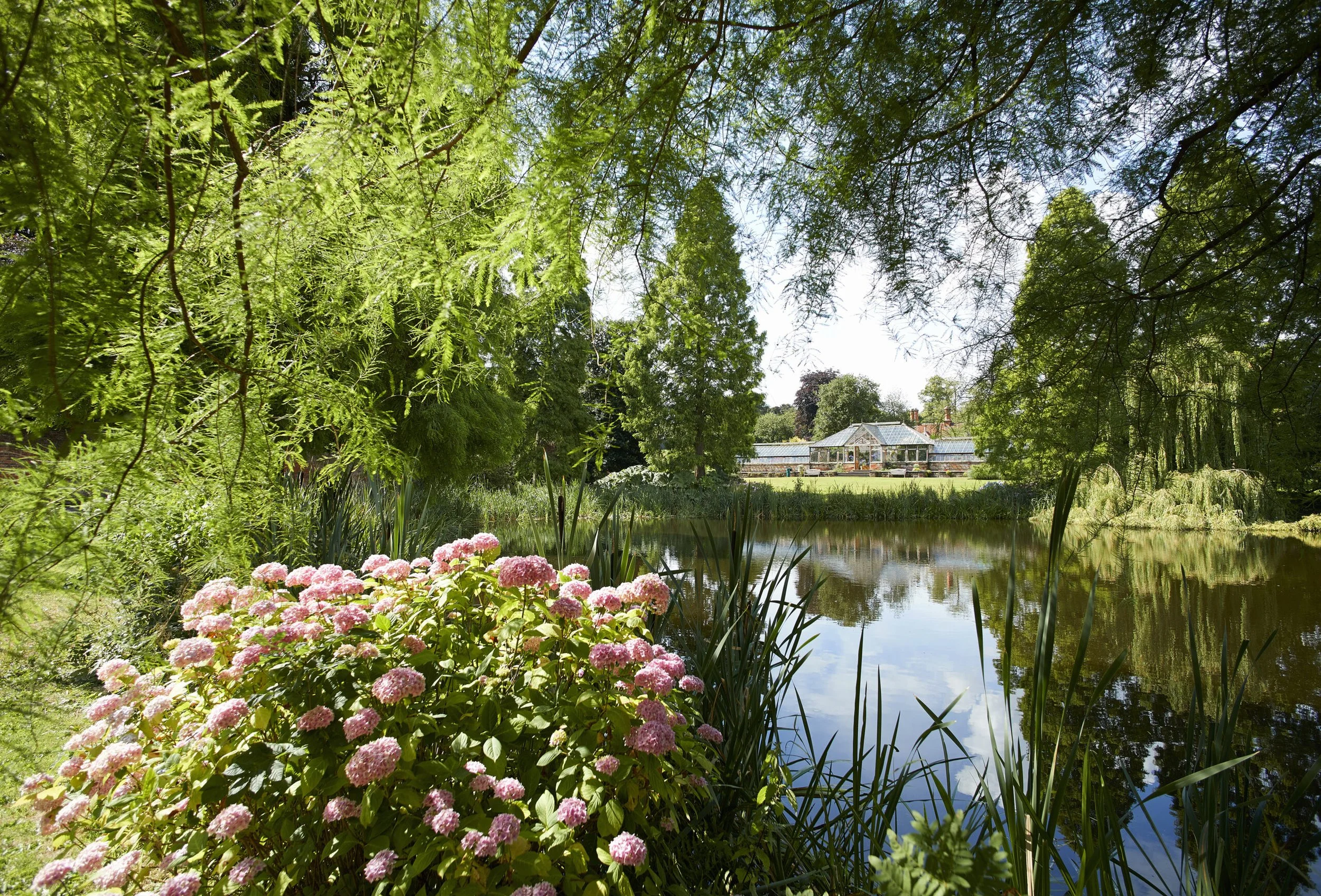 An aerial view of a coastal golf course with green fairways, sand traps, and surrounding trees, overlooking the ocean with a cloudy sky.