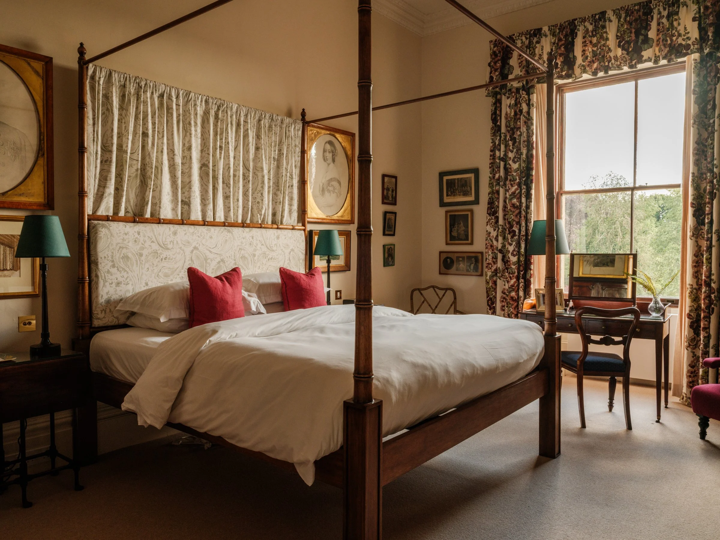 Elegant bathroom with a walk-in shower, a toilet with a black seat, a vintage-style sink, a large round mirror, wall-mounted lights, framed artwork, and decorative containers, with marble and painted wall surfaces.