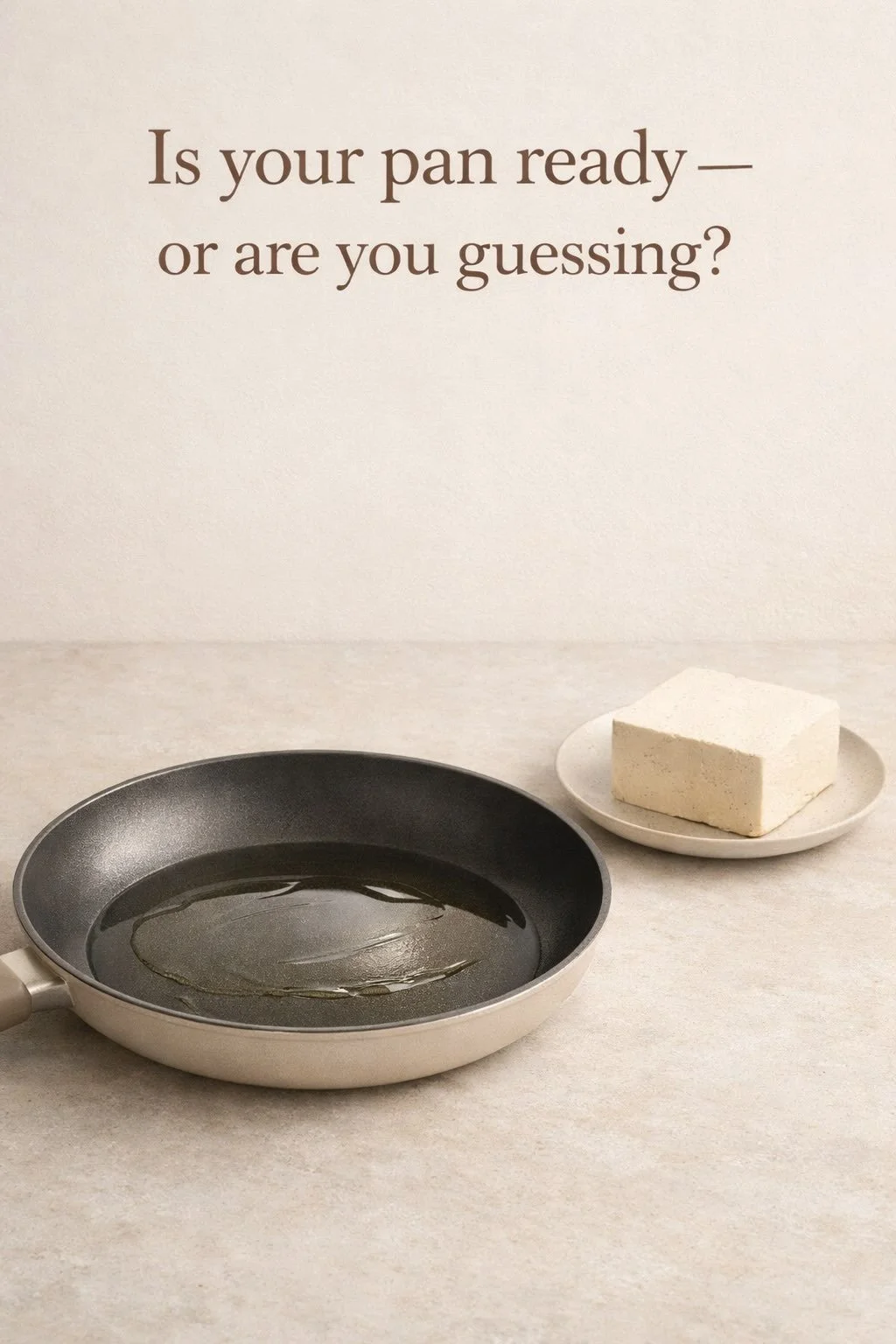 Pan with a thin layer of oil beside a block of tofu on a stone surface, shown before searing