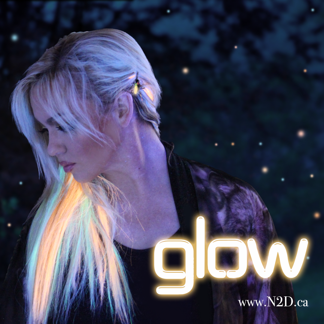 A woman with blonde hair and a glowing rainbow-colored streak, looking downward, with the word 'glow' in neon font and the website www.N2D.ca in small text.