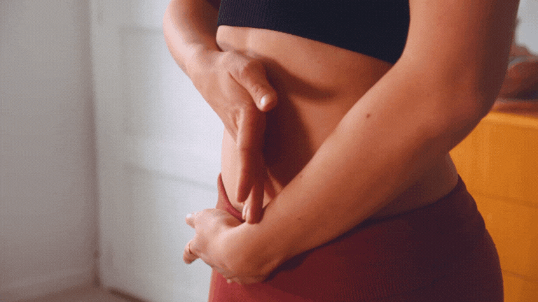 Nahaufnahme eines Frauenmundes, der eine Pillenpackung hält, in einem Schlafzimmer mit warmer Beleuchtung.