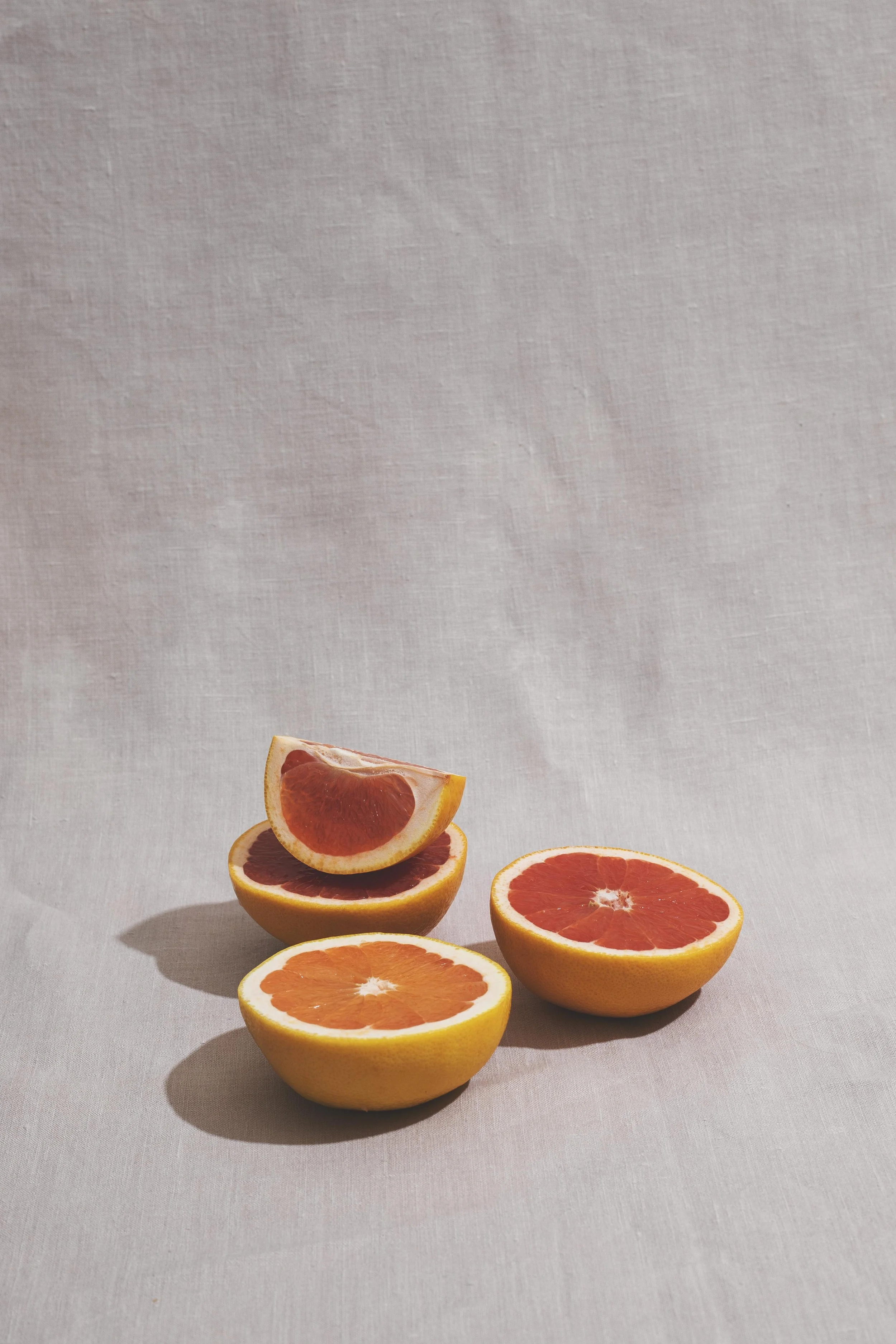 Geteilte Grapefruithälften und -stücke auf einem hellen Stoffhintergrund.