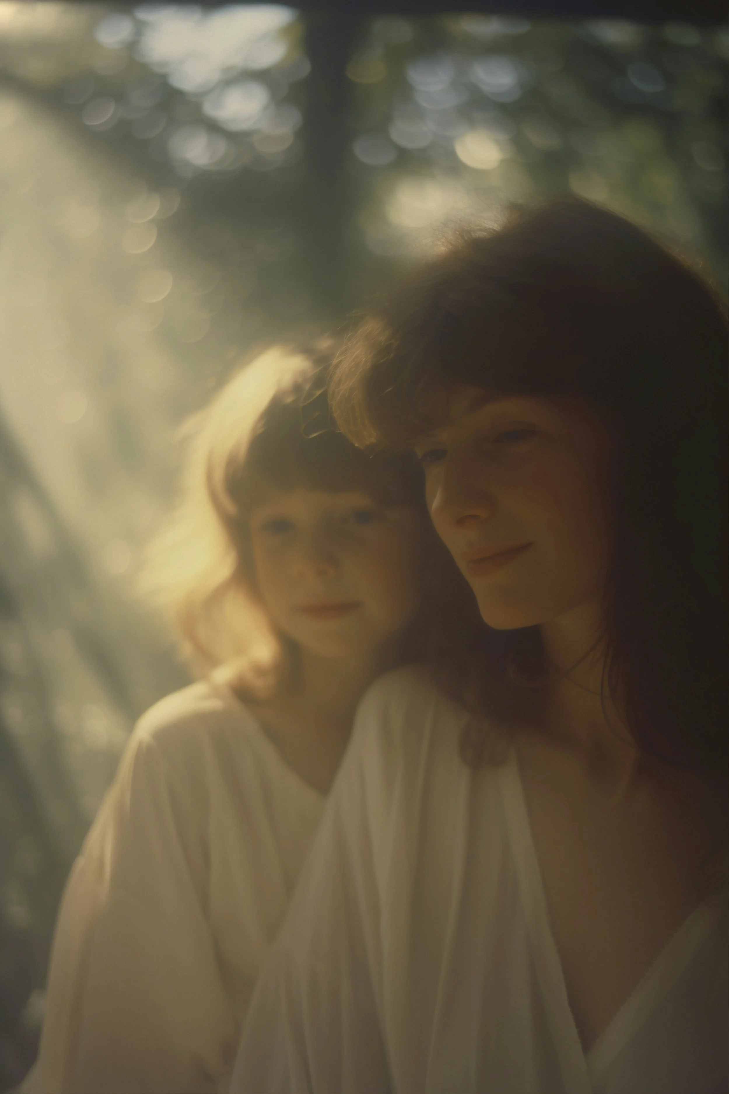 Zwei Frauen in einem Sonnenlicht-idyllischen Wald mit weichen Lichtstrahlen, die durch die Bäume scheinen.