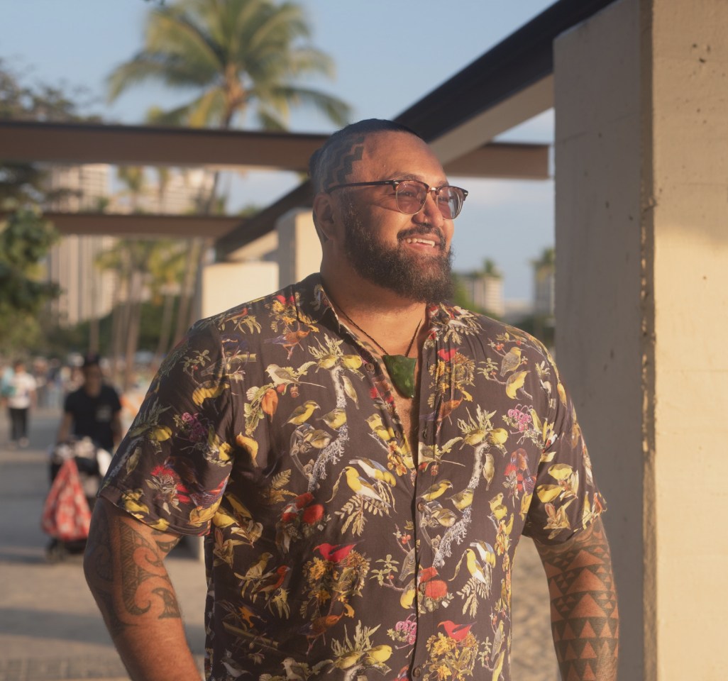 Smiling Pasifika Man wearing glasses, looking into the distance to the left