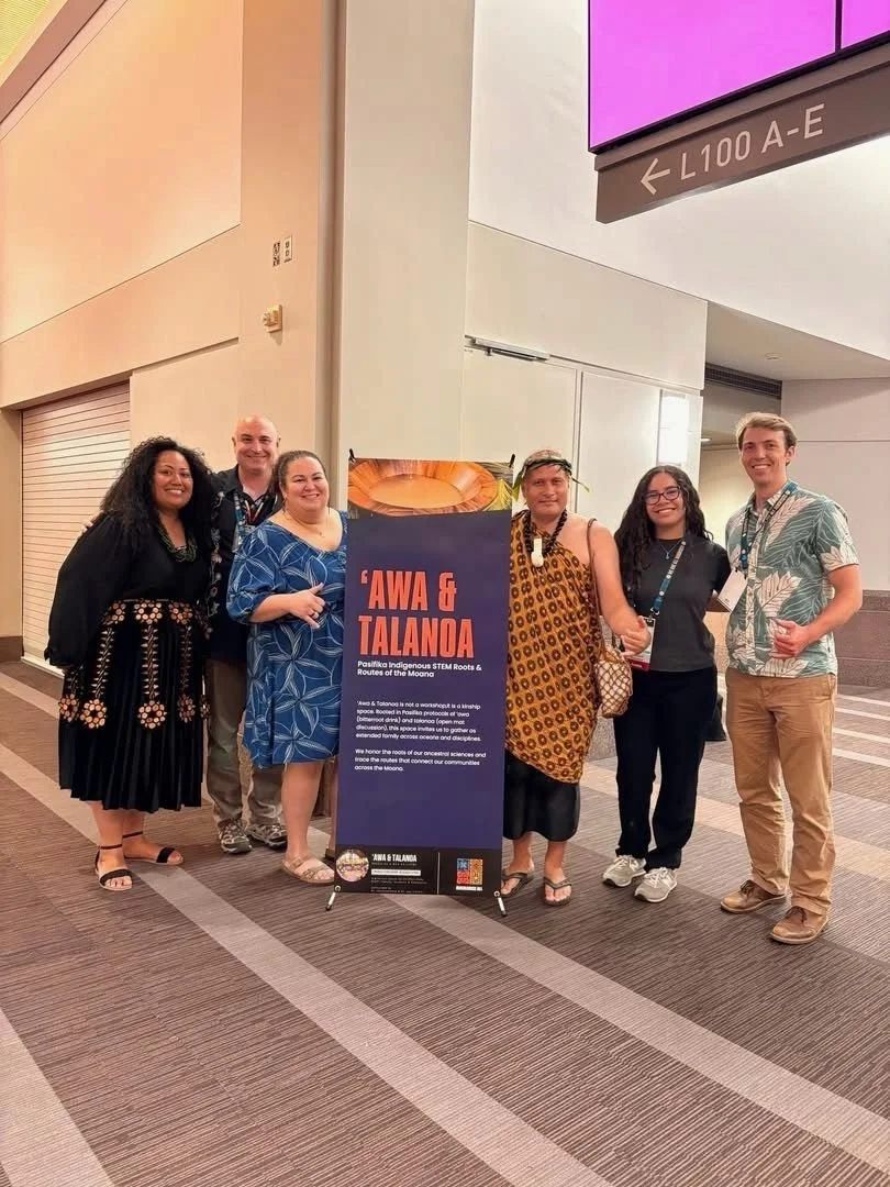 Group of six diverse people standing in front of a sign that reads 'AWA & TALANOA,' with details about Pasifika Indigenous STEM roots and routes of the Moana, in an indoor conference space.