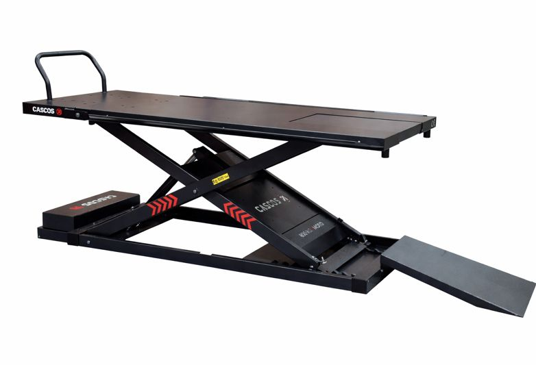 Une table de levage mécanique noir avec une surface rectangulaire et une rampe pour accès, utilisée pour le service ou la réparation de véhicules.