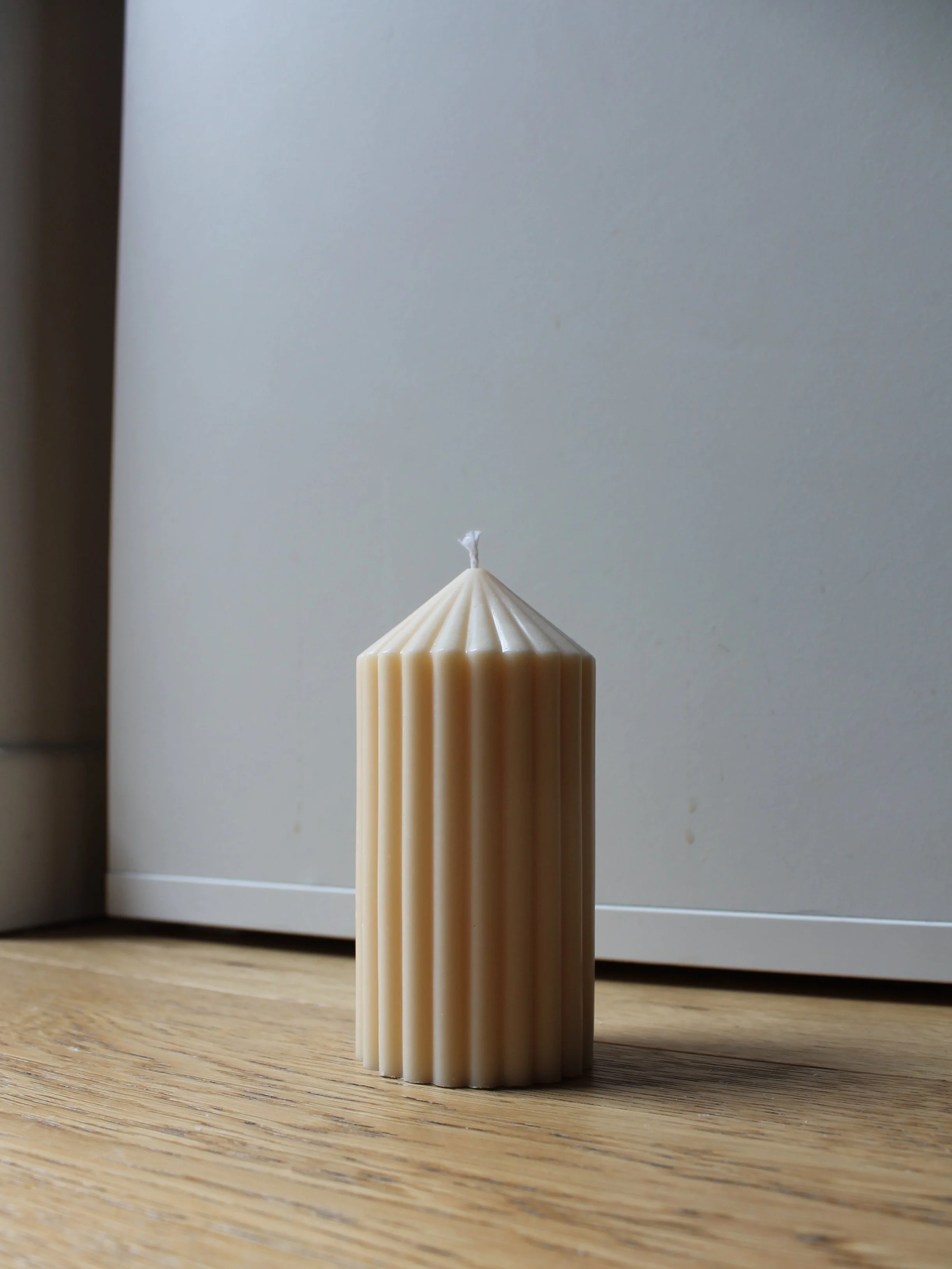 A single candle placed on a table against a plain white background.