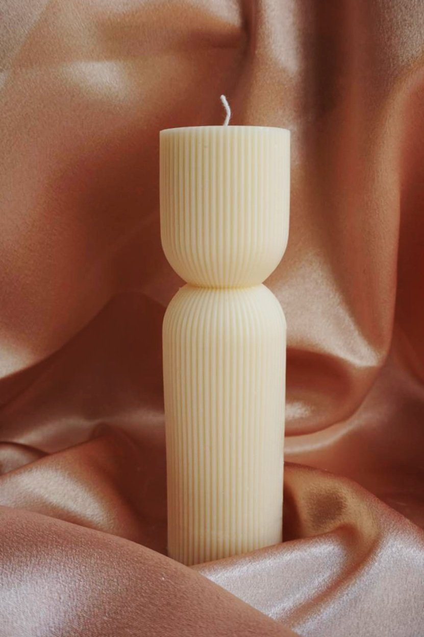 A lit candle placed on a table covered with a brown cloth, creating a warm and inviting atmosphere.