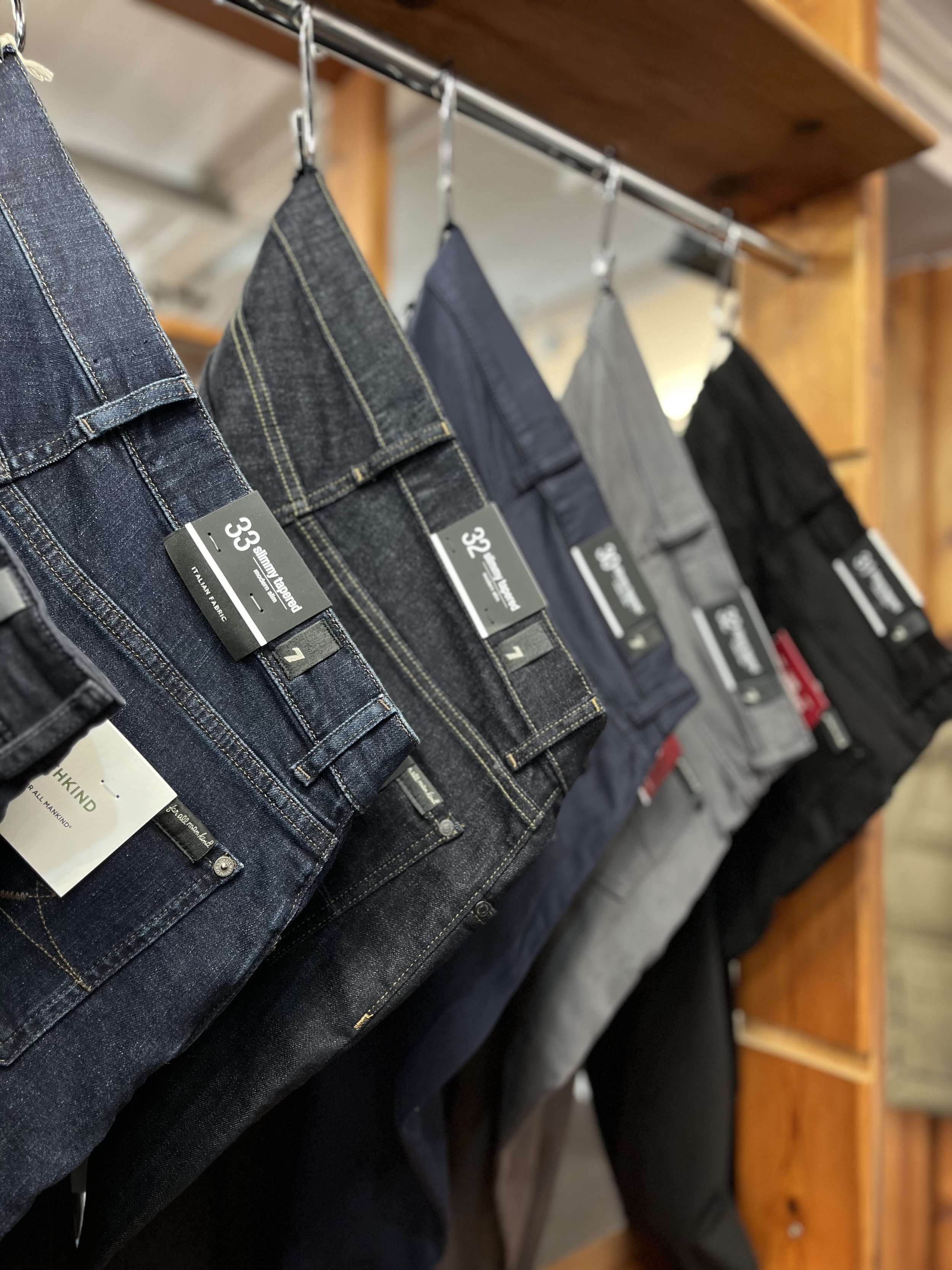 Jeans display on hangers in a store, showing various colors and sizes.