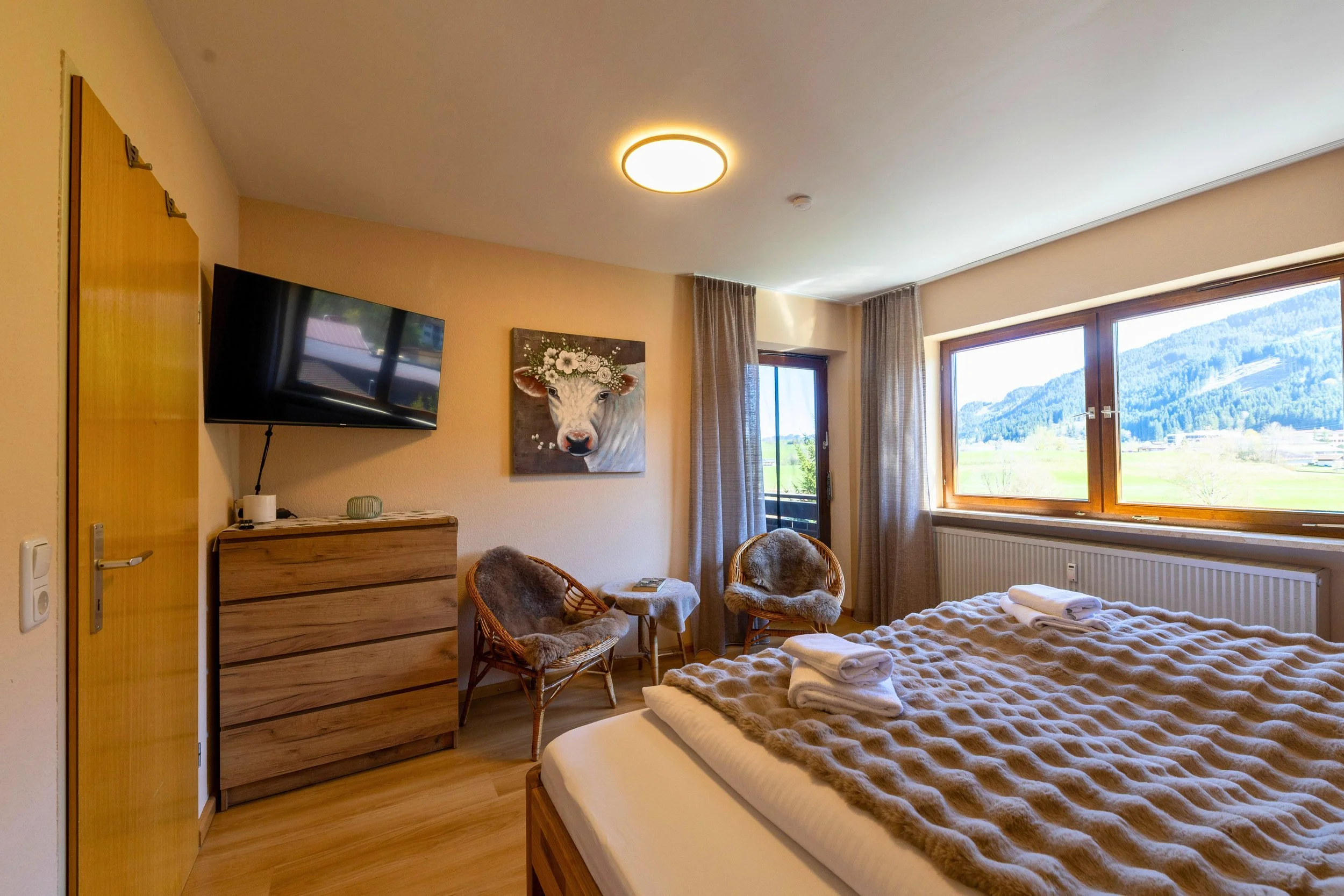 Großzügiges Schlafzimmer mit Familienbett (240 × 200 cm), Smart-TV und direktem Zugang zum Südbalkon.