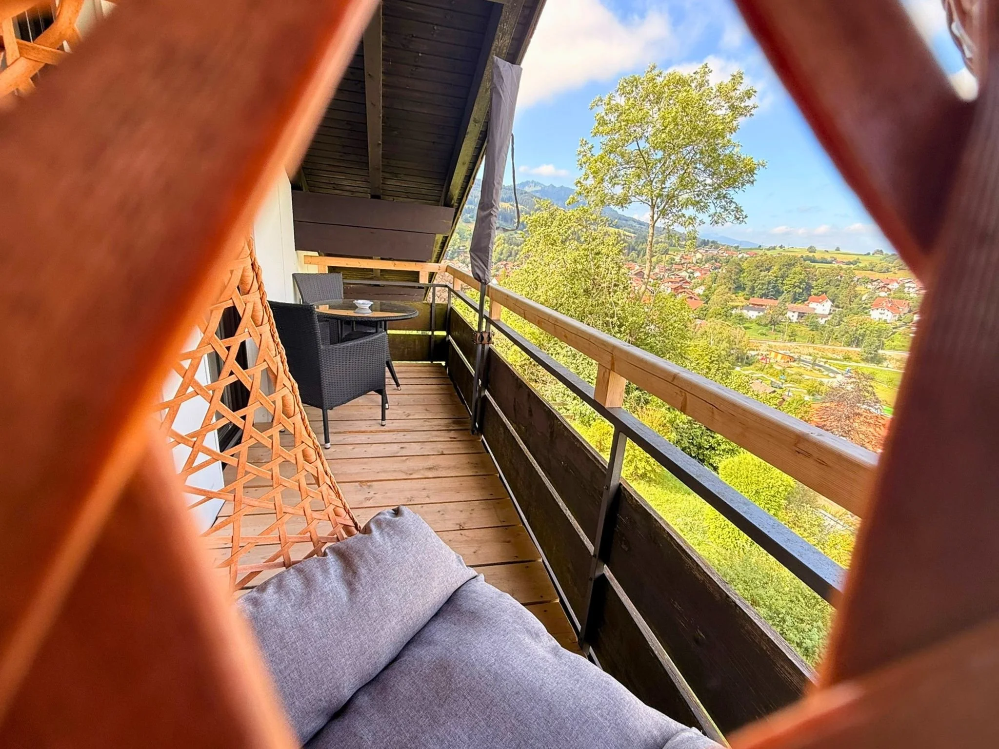 Gemütlicher Westbalkon mit Rattan-Hängesessel, Sitzgelegenheiten und Sonnenschirm