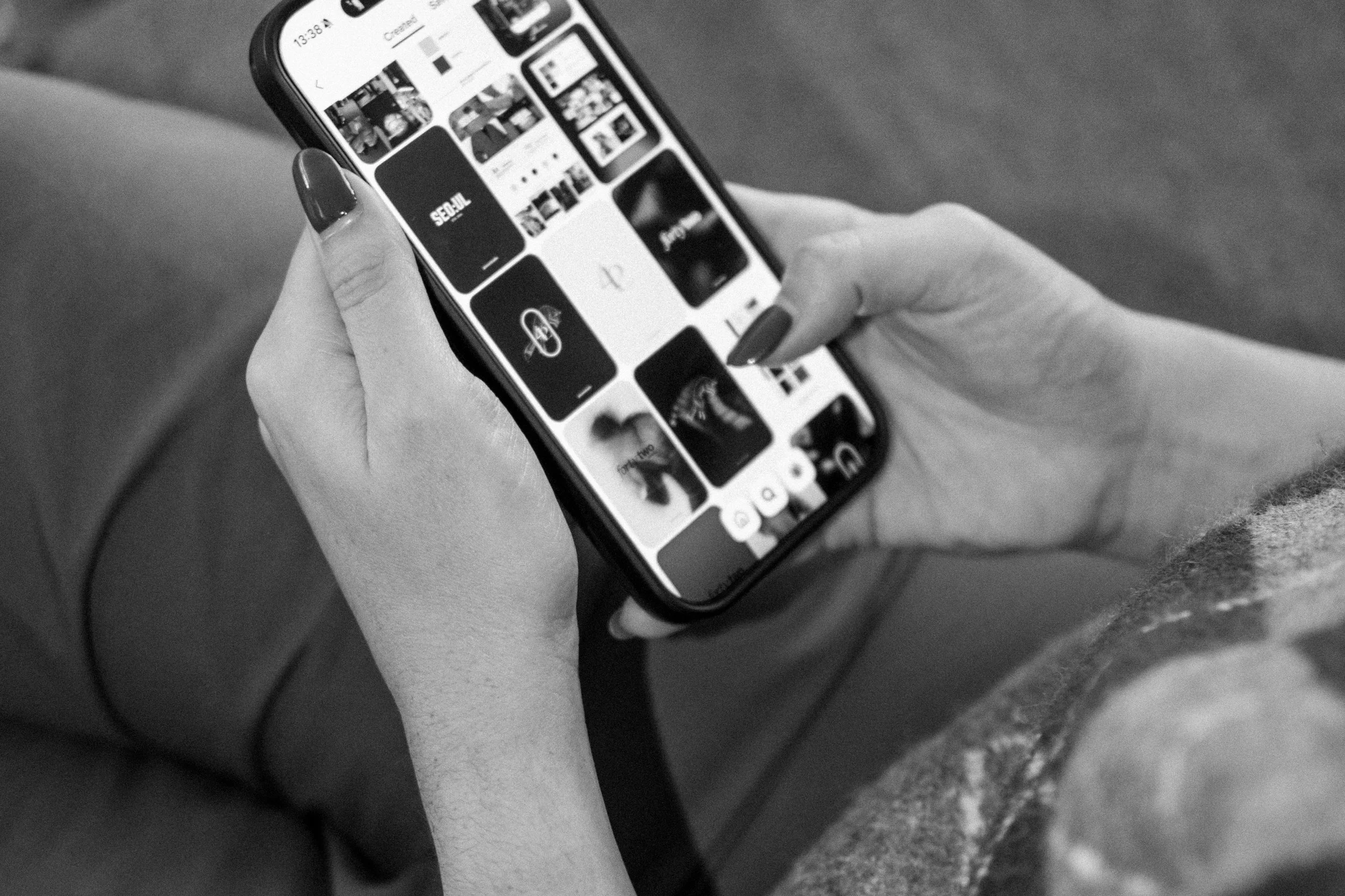 A person's hand holding a smartphone, displaying a photo gallery with various images, including one labeled 'SEOUL.' The background is blurred.