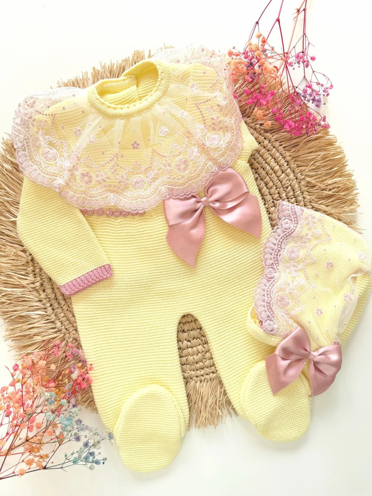 Deluxe Hand-Knitted Newborn Romper Set, includes bonnet, in soft yellow with dusty pink bow detail. Perfect as a coming home outfit.