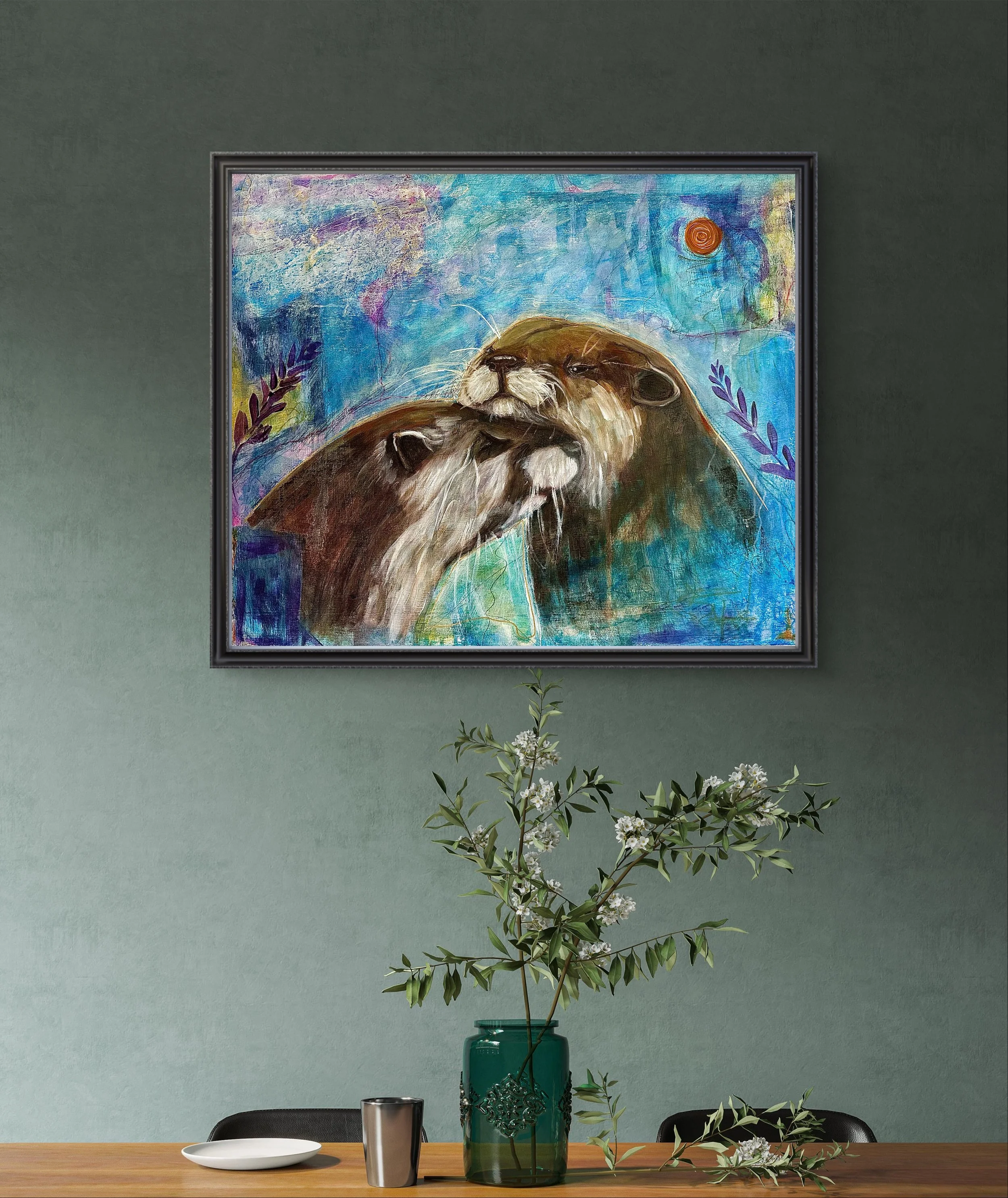 Colorful abstract painting of two otters on a green wall above a wooden table with a green vase holding branches with white flowers, a white plate, and a metallic cup.