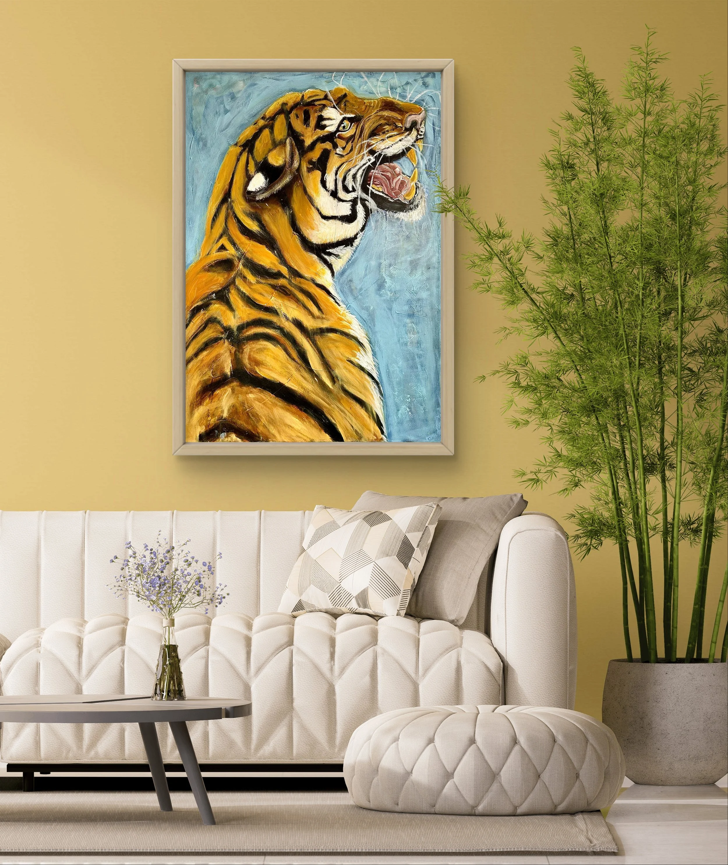 A living room with a cream-colored tufted sofa, a gray and white patterned pillow, a small personalized ottoman, a glass vase with purple flowers on a black coffee table, a large green plant in a gray pot, and a vibrant painting of a roaring tiger on a yellow wall.