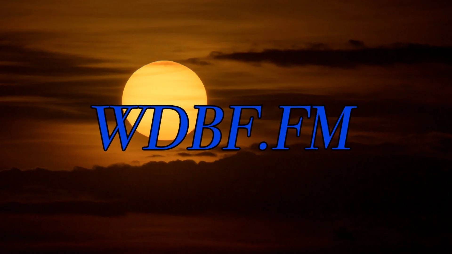 A sunset or sunrise scene with a bright sun partially obscured by clouds and dark foreground, with the text 'WDBF.FM' in large blue letters overlayed on the image.