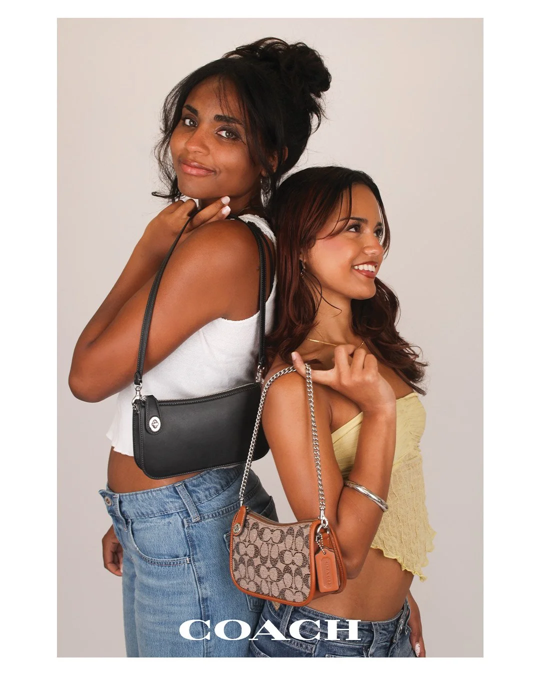 Two young women stand close together, one behind the other, holding designer handbags, with the COACH logo at the bottom.