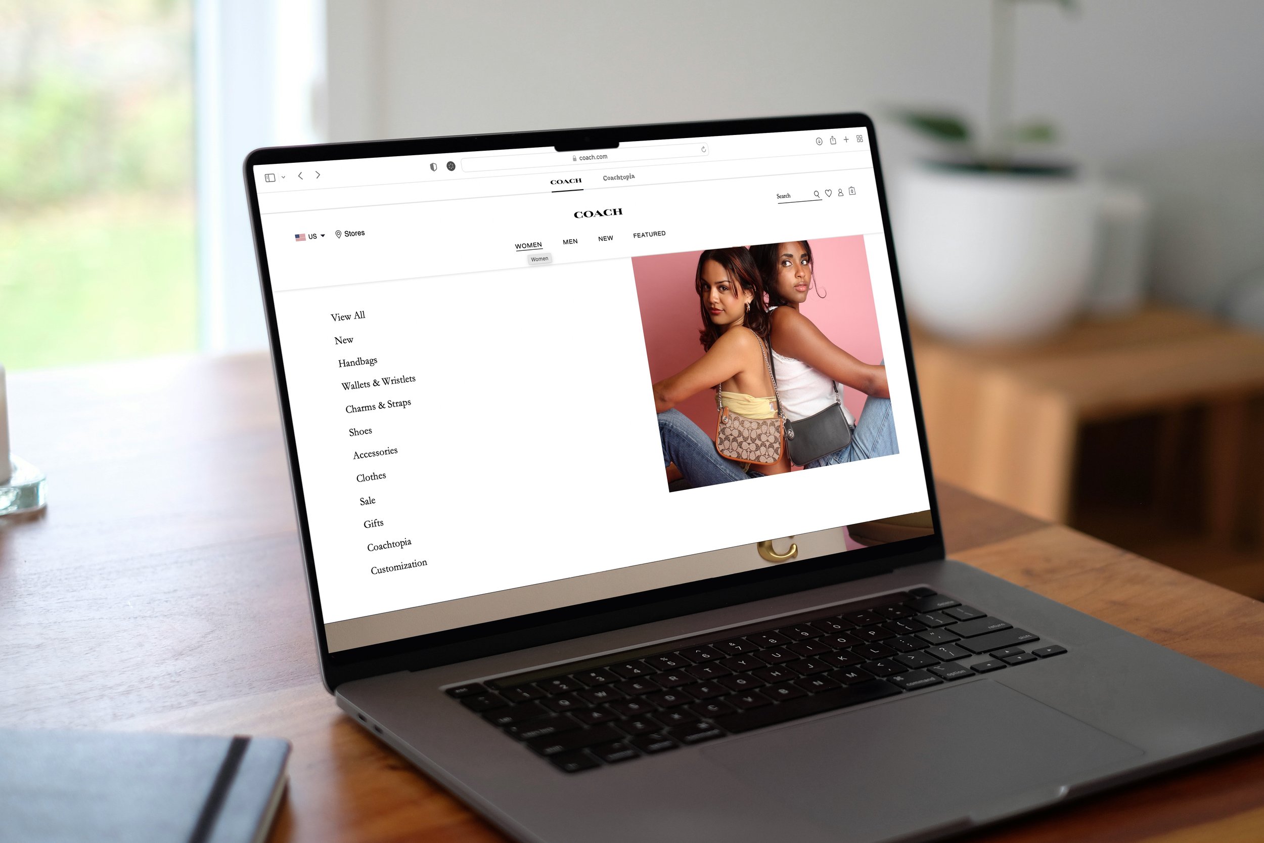 Laptop displaying the Coach online store with handbags and a model.