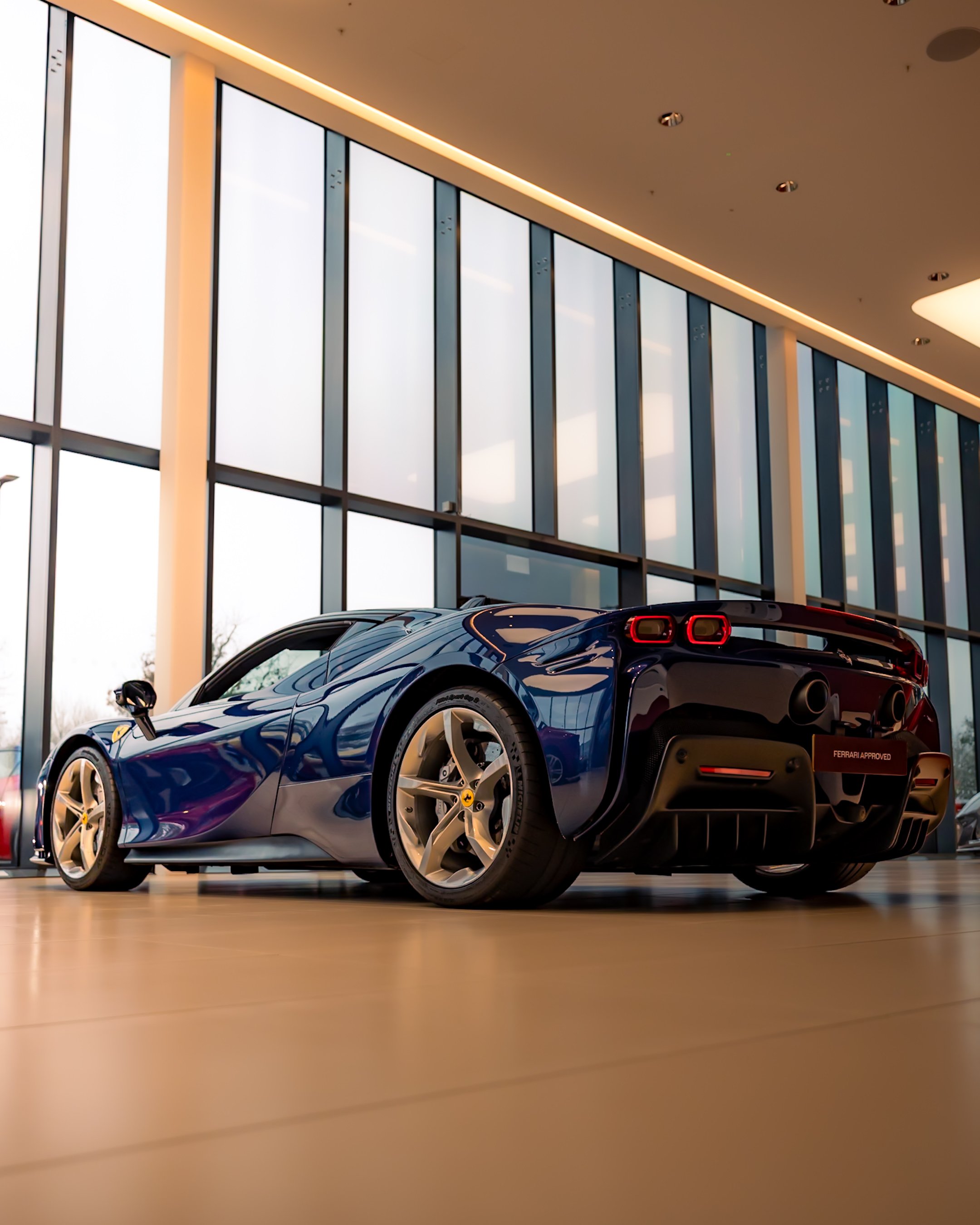 Blue sports car with sleek design showcased inside a modern showroom with large windows.