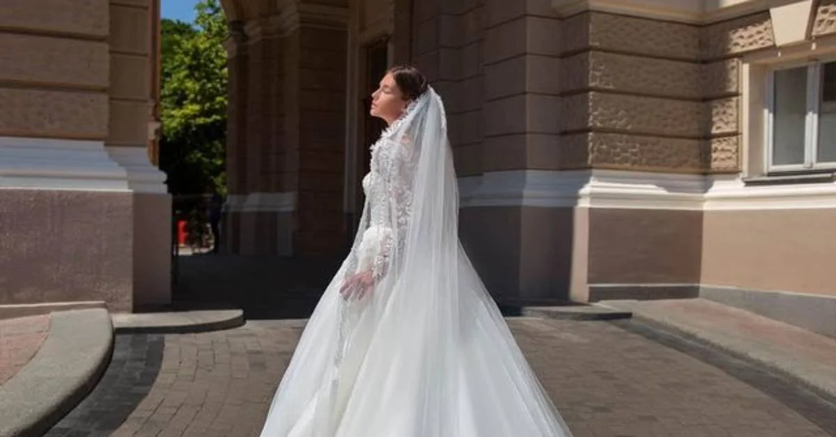 Bride wearing a dramatic cathedral-length veil with intricate lace detailing, creating a graceful and sophisticated bridal look for a formal wedding celebration.