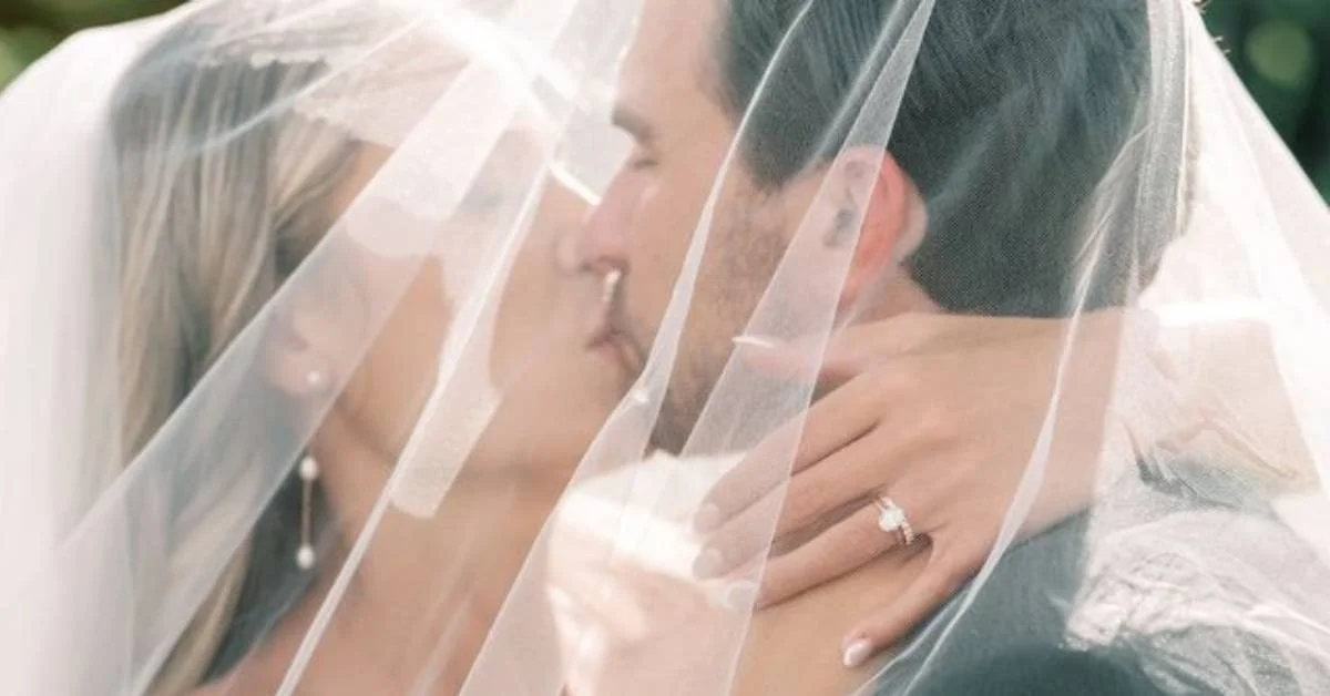 Romantic wedding portrait capturing an intimate moment between newlyweds beneath a delicate bridal veil, highlighting elegance, emotion, and timeless wedding-day beauty.