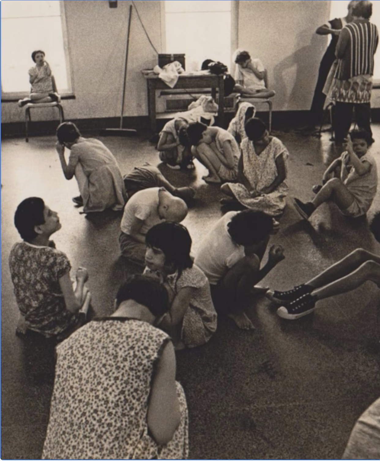 An image from Willowbrook State School, which was an institute for people with IDD, shows a group of girls with IDD sitting on the floor, many with their head in their knees in distress.