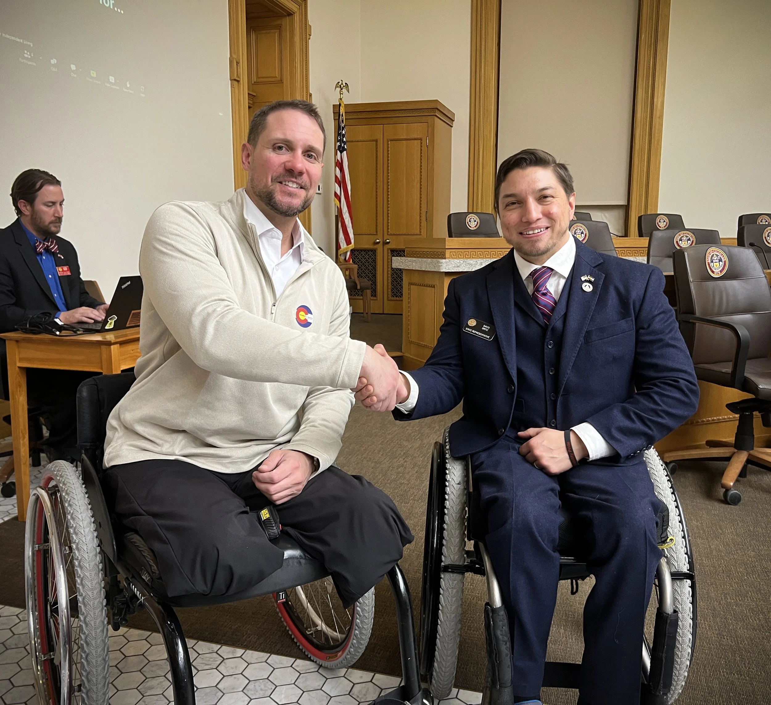 Craig Towler, the Director of Public Policy & Advocacy for CPWD, shakes hands with Rep. David Ortiz. Both are wheelchair users.