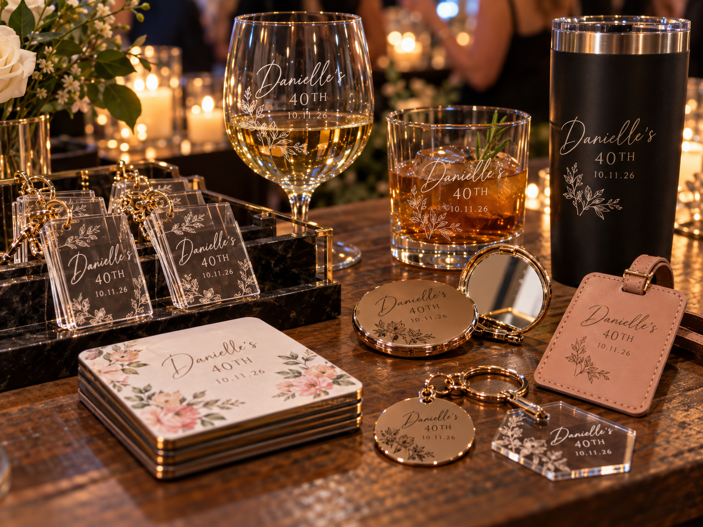 A display of personalized decor and accessories for Danielle's 40th birthday celebration, including engraved cards, a glass with wine, a tumbler with a drink, a mini mirror, keychains, and a pink leather ID holder, all featuring her name and the date 10.11.26.