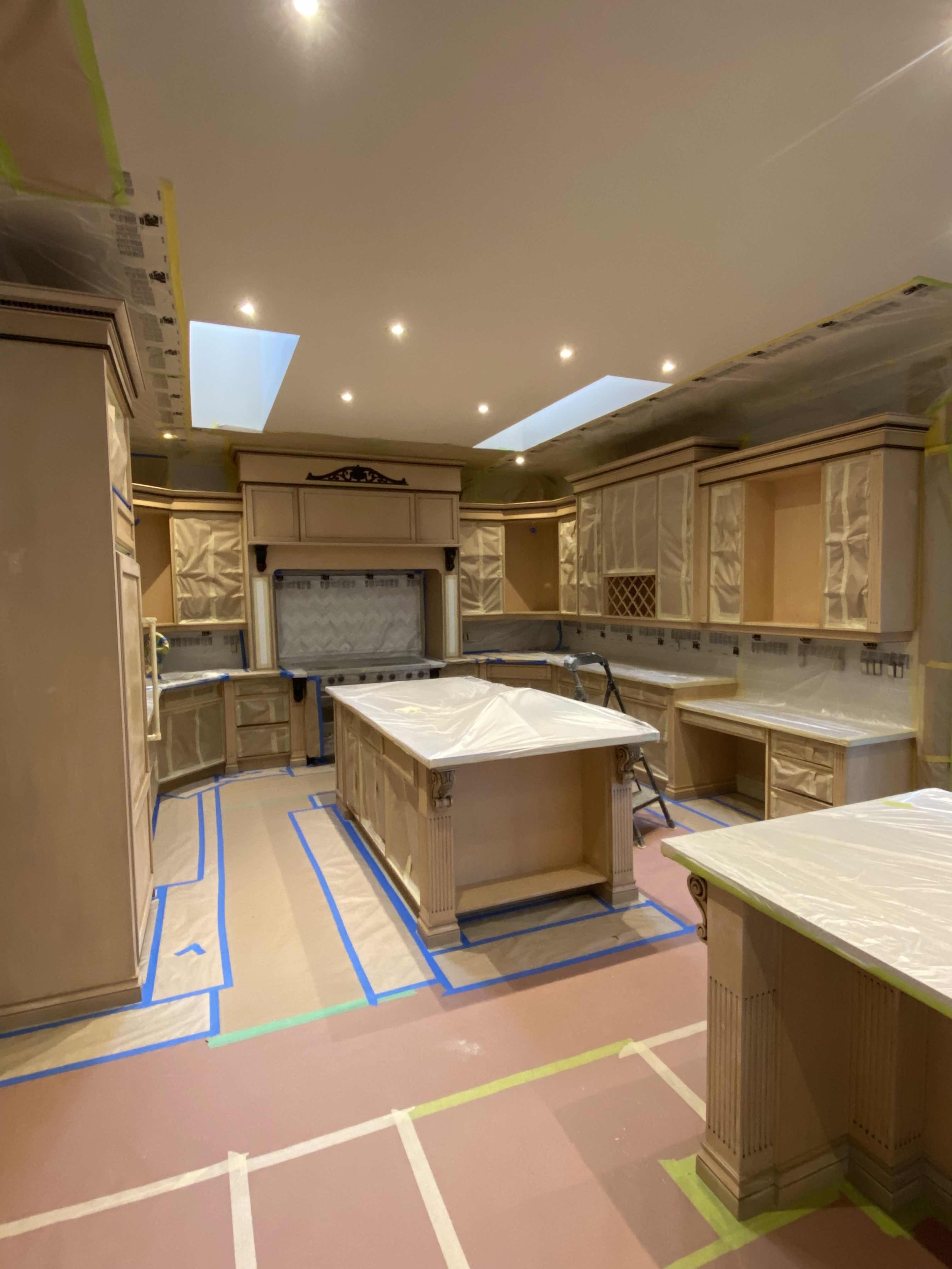 Large kitchen under renovation with covered cabinets and counters, recessed lighting, and a central island.