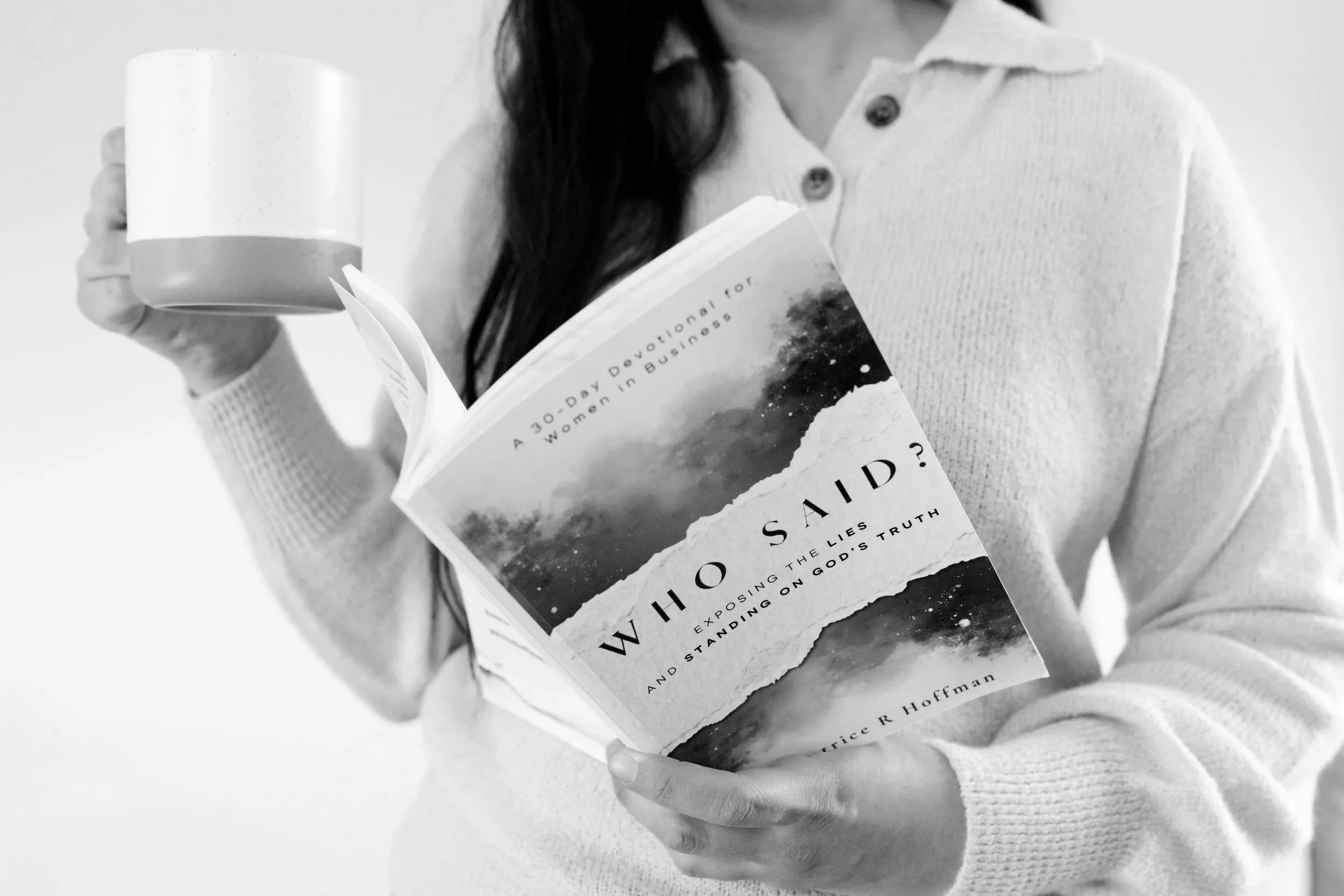 A woman holding a book titled 'Who Said? The Lies Exposing the Truth and Standing on God's Truth' and a coffee mug, wearing a light-colored sweater.