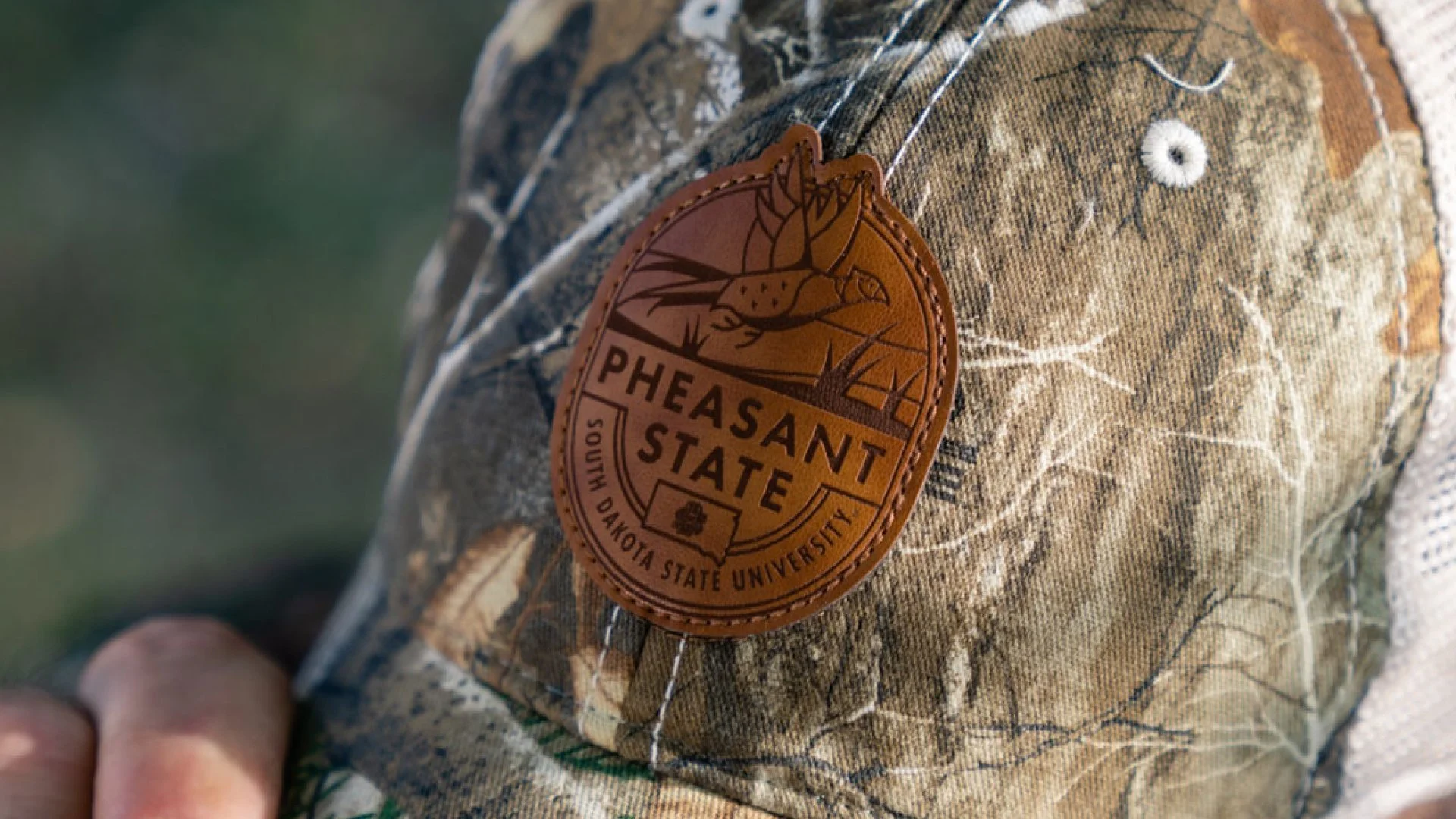 A camo hat with a Pheasant State patch logo