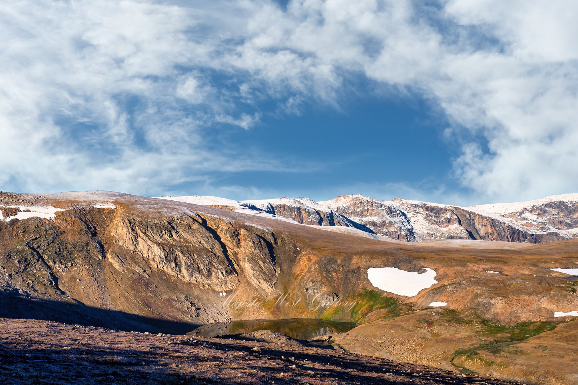 Mountain scene with small pond on a beautiful day with blue sky and white clouds
