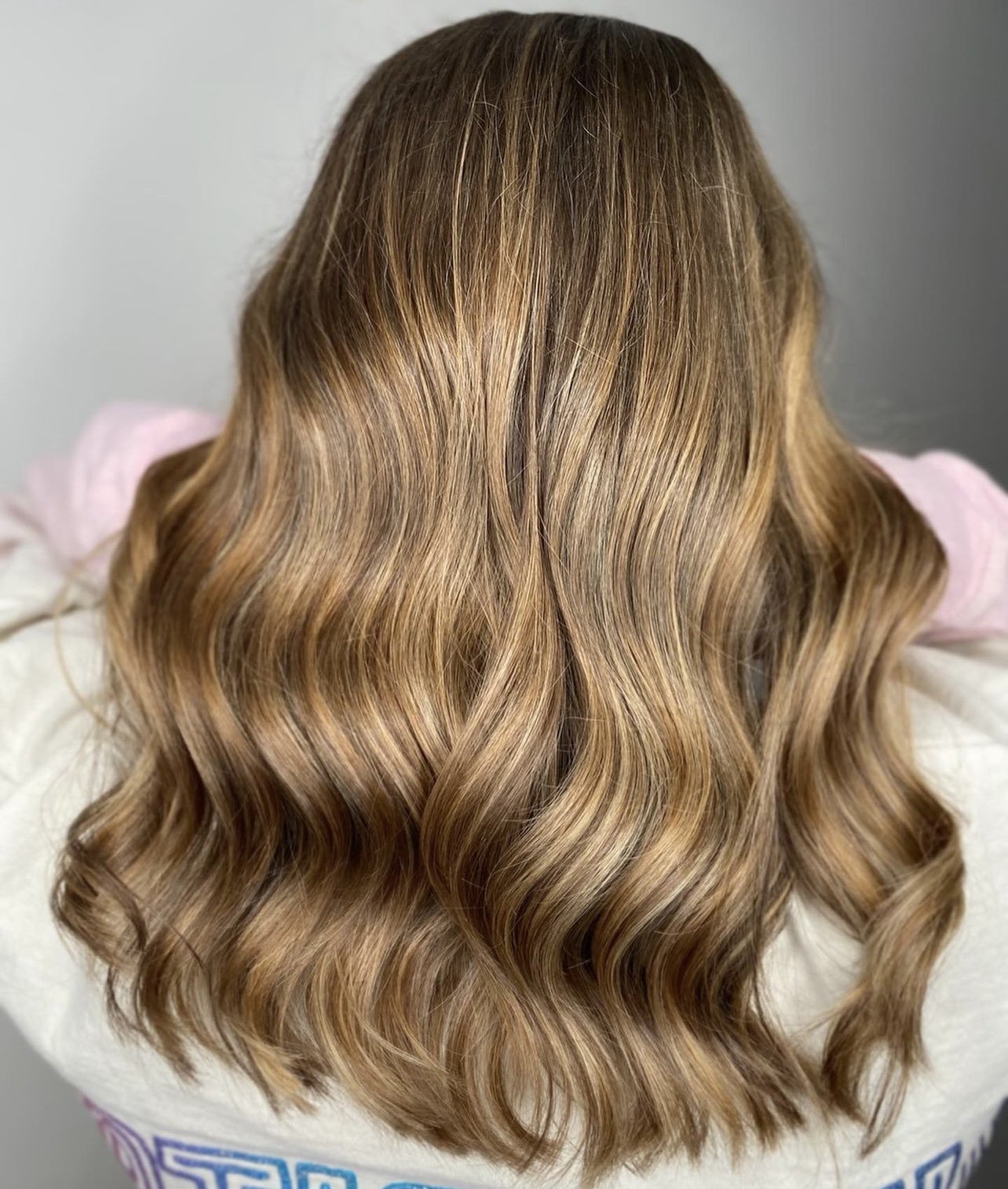 Back of a person's head with wavy, light brown hair.