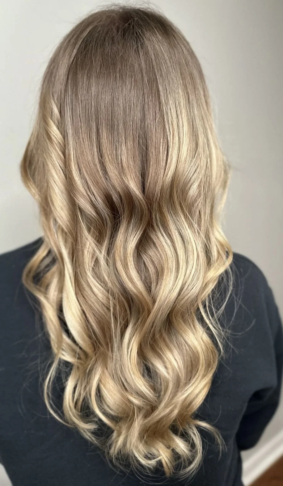 Back view of a person with long, wavy blonde hair.