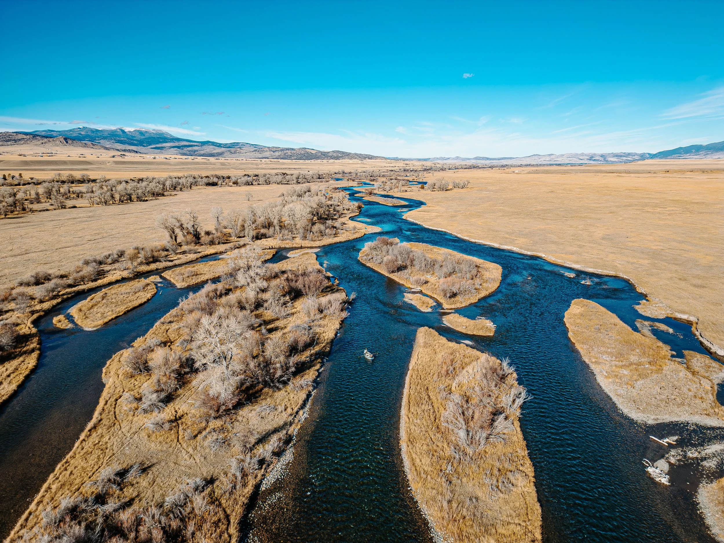 Wide Angle aerial photo of a drift boat floating down the madison river on a guided fly fishing trip in Montana