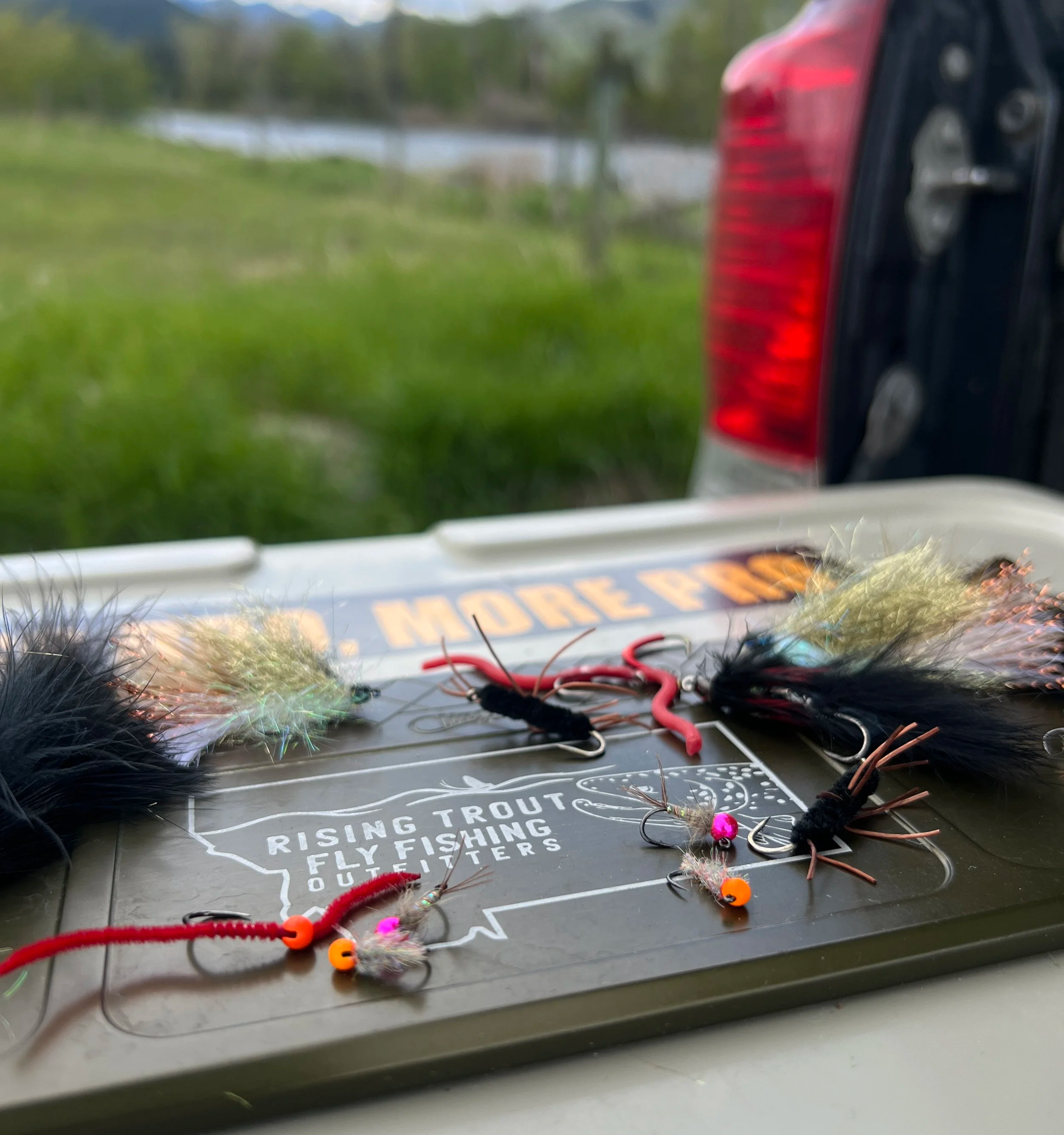 Fishing lures placed on a toolbox with an outdoor landscape in the background