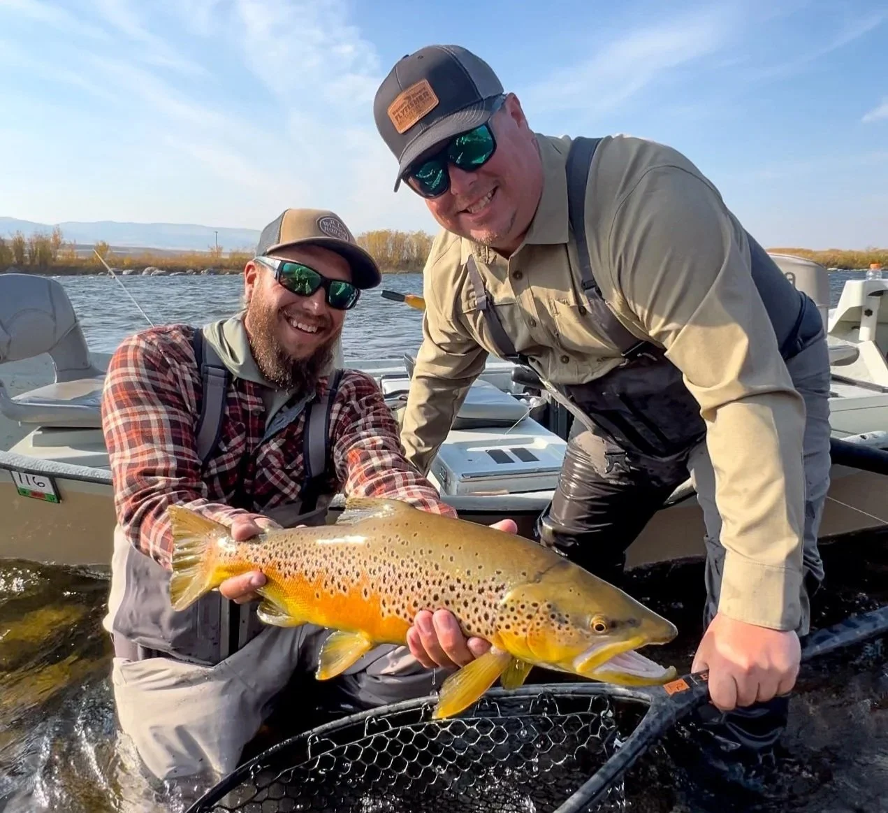 guide and client holding a large brown trout in fall on the upper madison river