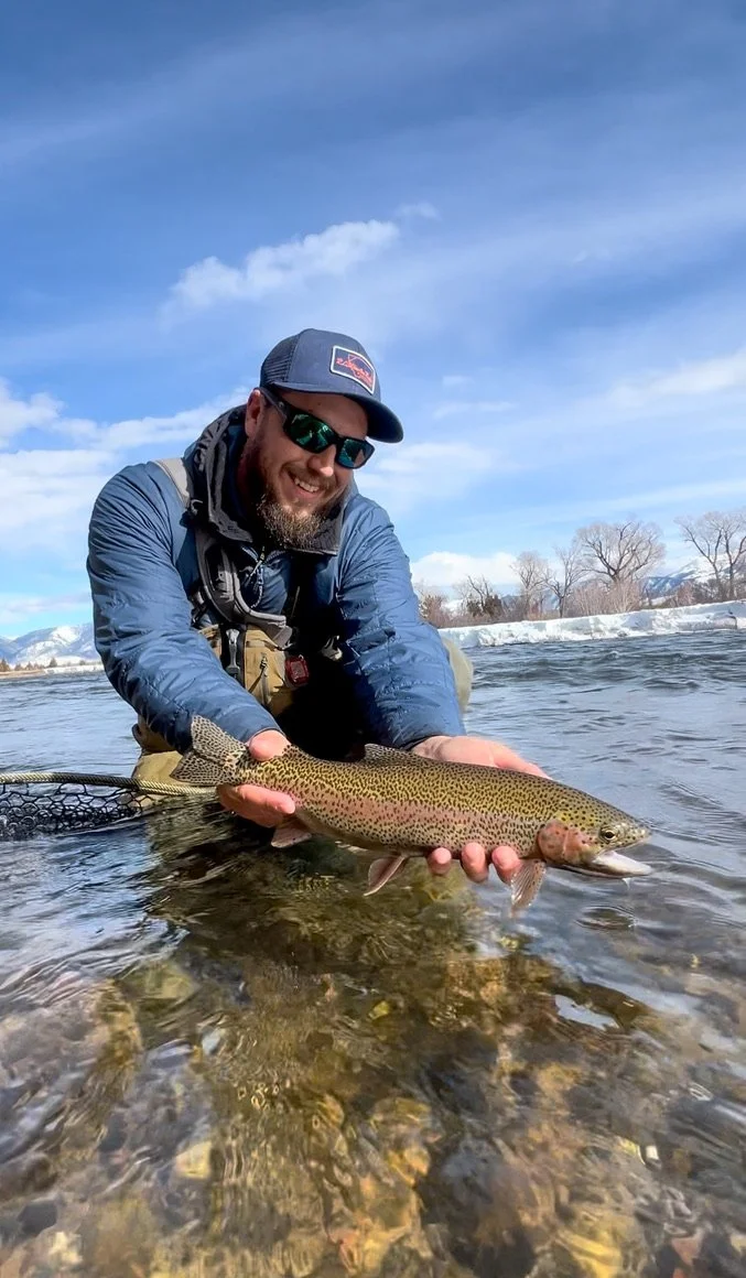 Angler holding a rainbow trout caught on the upper madison river in winter