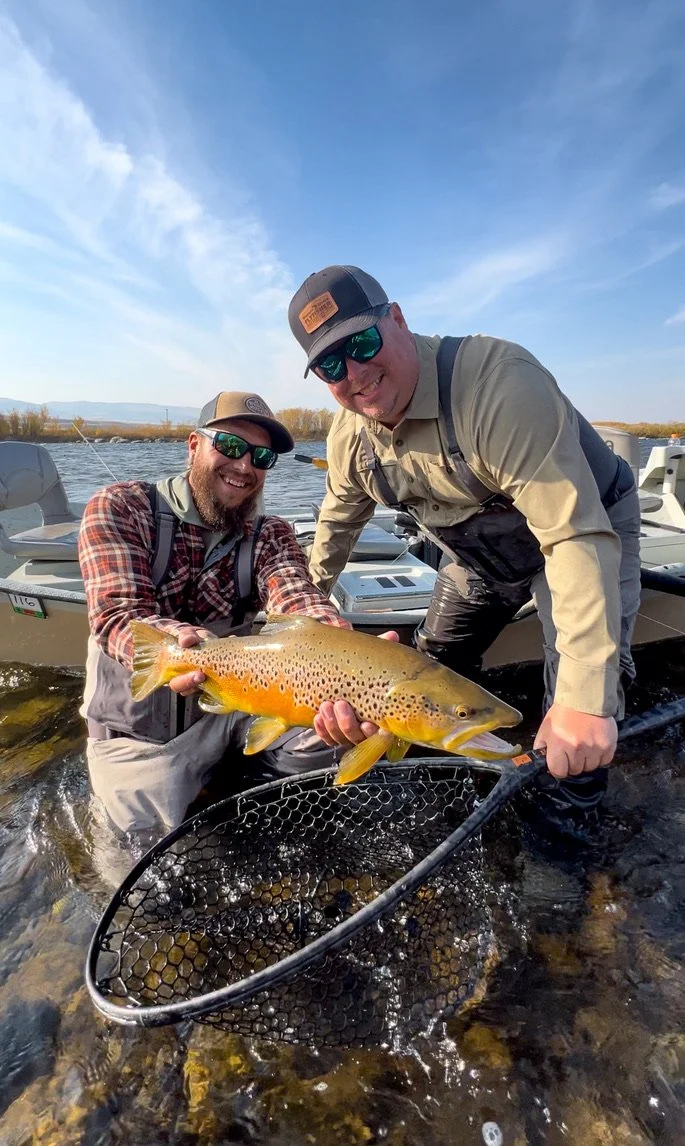 Angler and fly fishing guide holding a big brown trout on the Madison River in montana