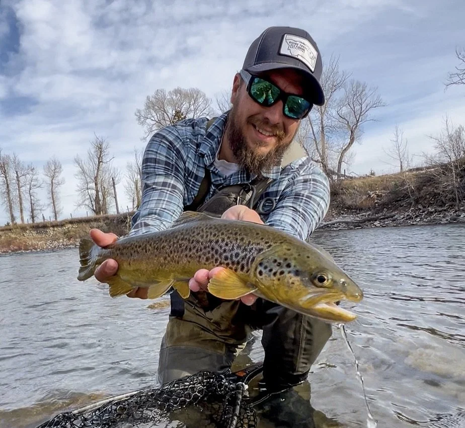 Angler holding a brown trout on the gallatin river