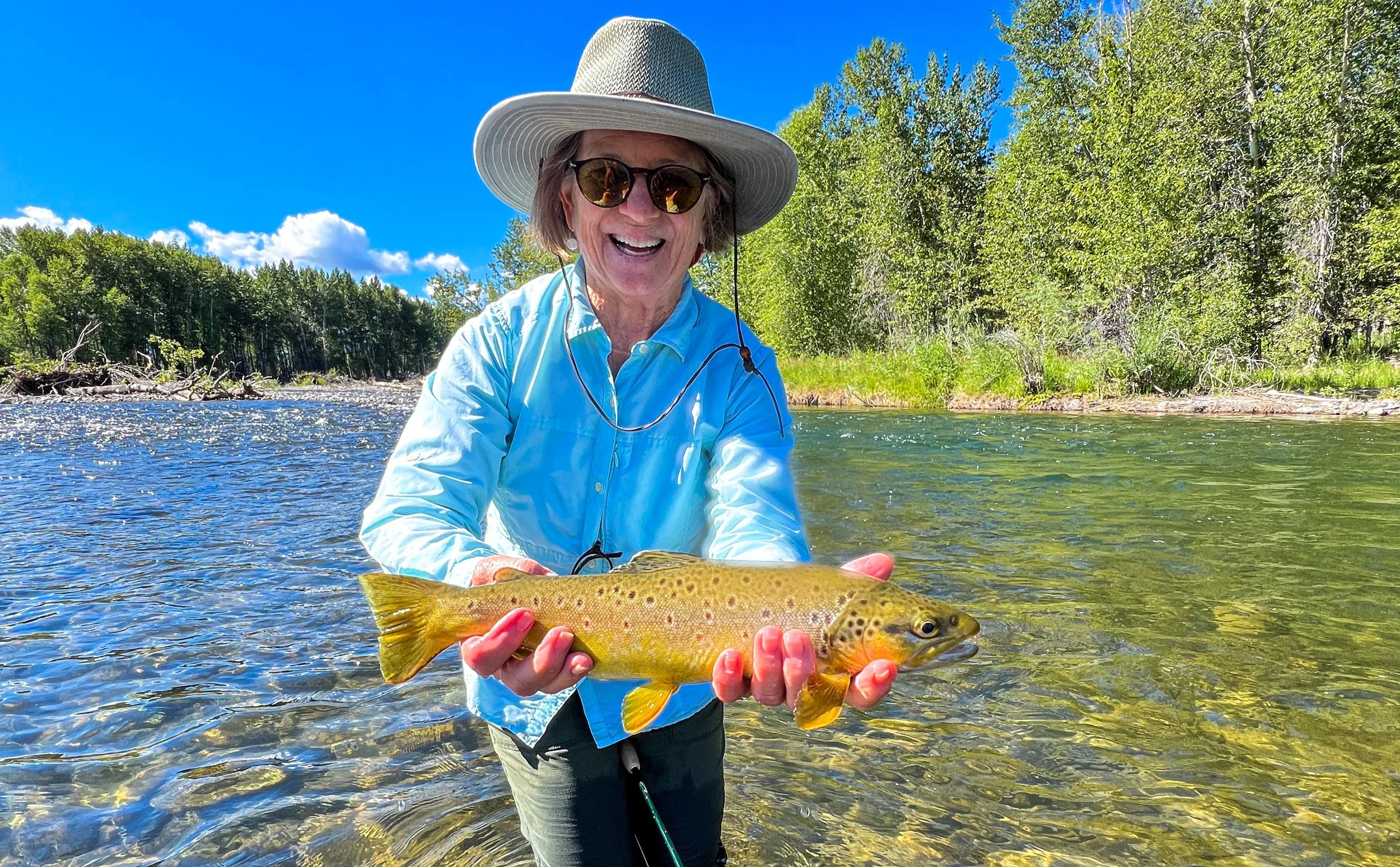 Angler holding a brown trout caught on a walk wade fly fishing guide trip in Bozeman Montana on the Gallatin River